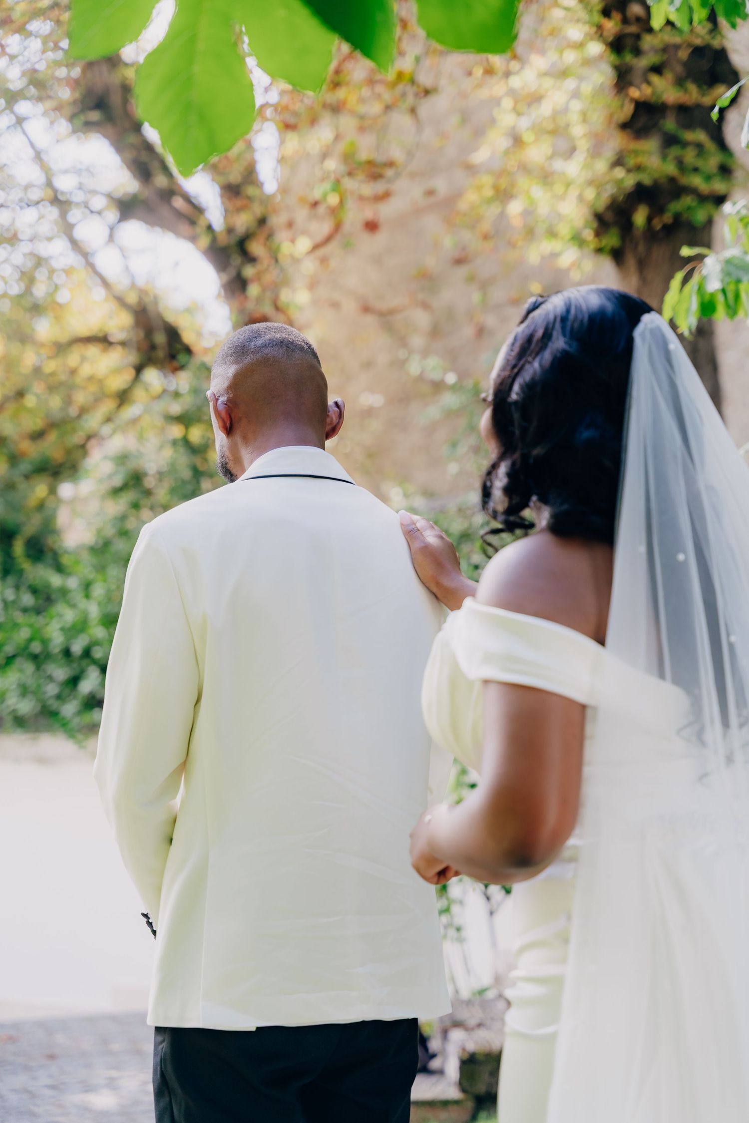 A wedding couple walks together on a garden path under green foliage on their special day.