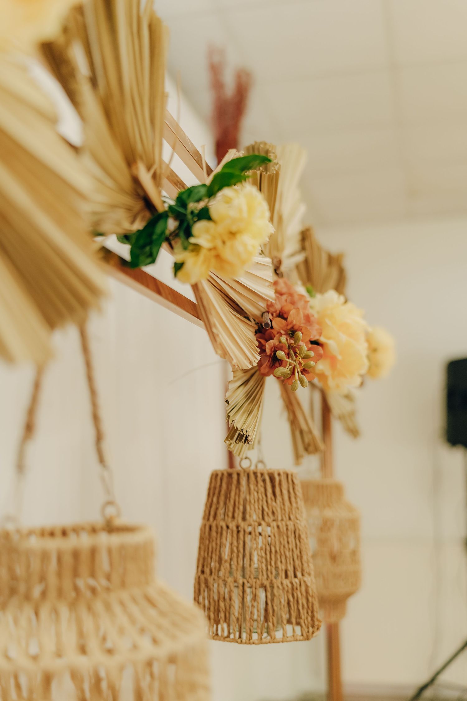 Woven rattan pendant light with dried flowers and wheat stalks in natural boho style decor arrangement.