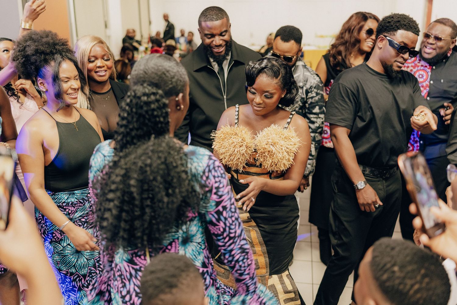 A festive gathering with people dancing and socializing in formal attire at an indoor celebration.