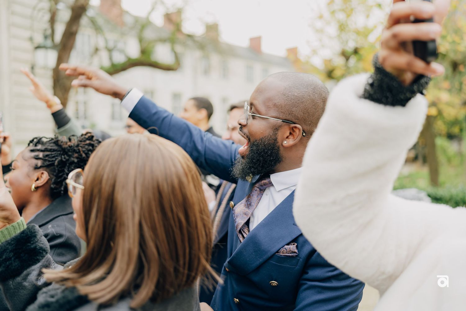 Wedding guests celebrating outdoors with joyful expressions and raised arms.