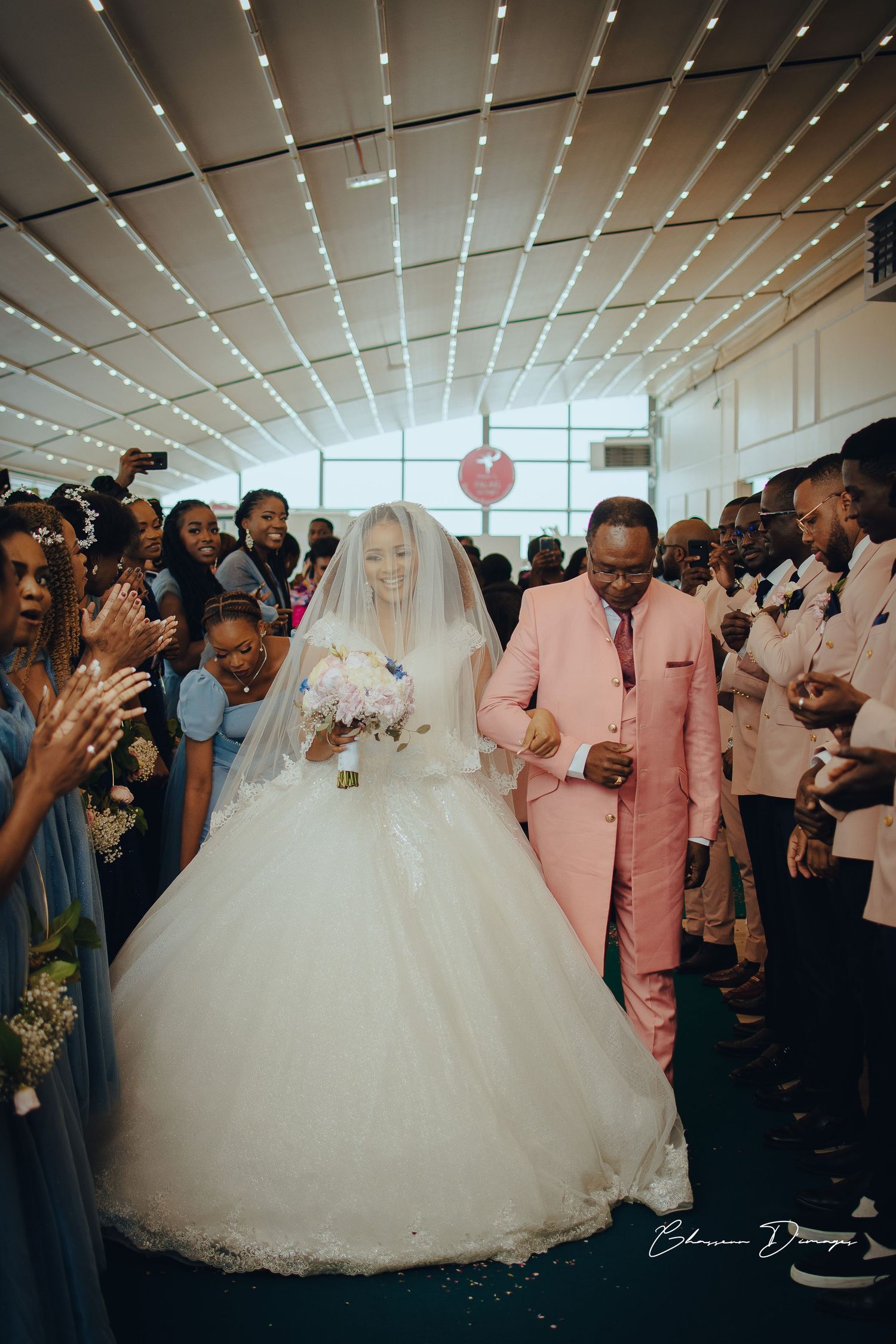 Grand wedding entrance under modern ceiling with cheering guests.