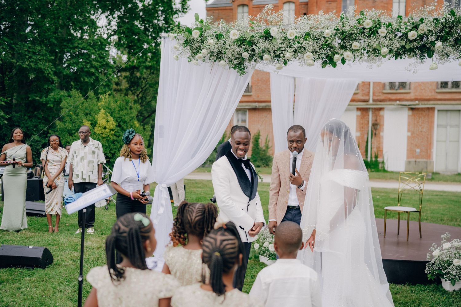 Outdoor wedding venue with white draping and chairs set up on grass.