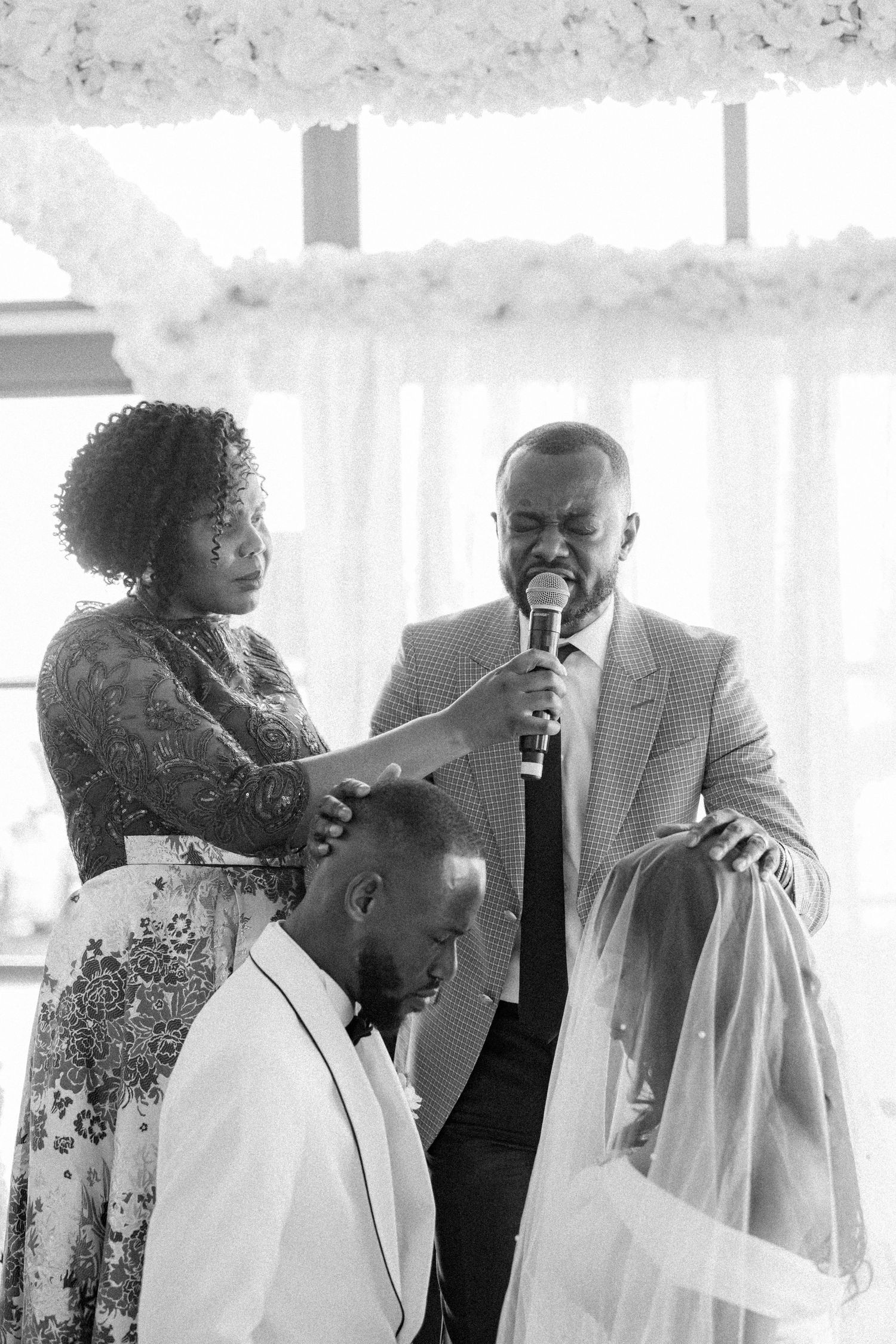 Black and white photo of wedding ceremony with speakers and guests gathered around couple.