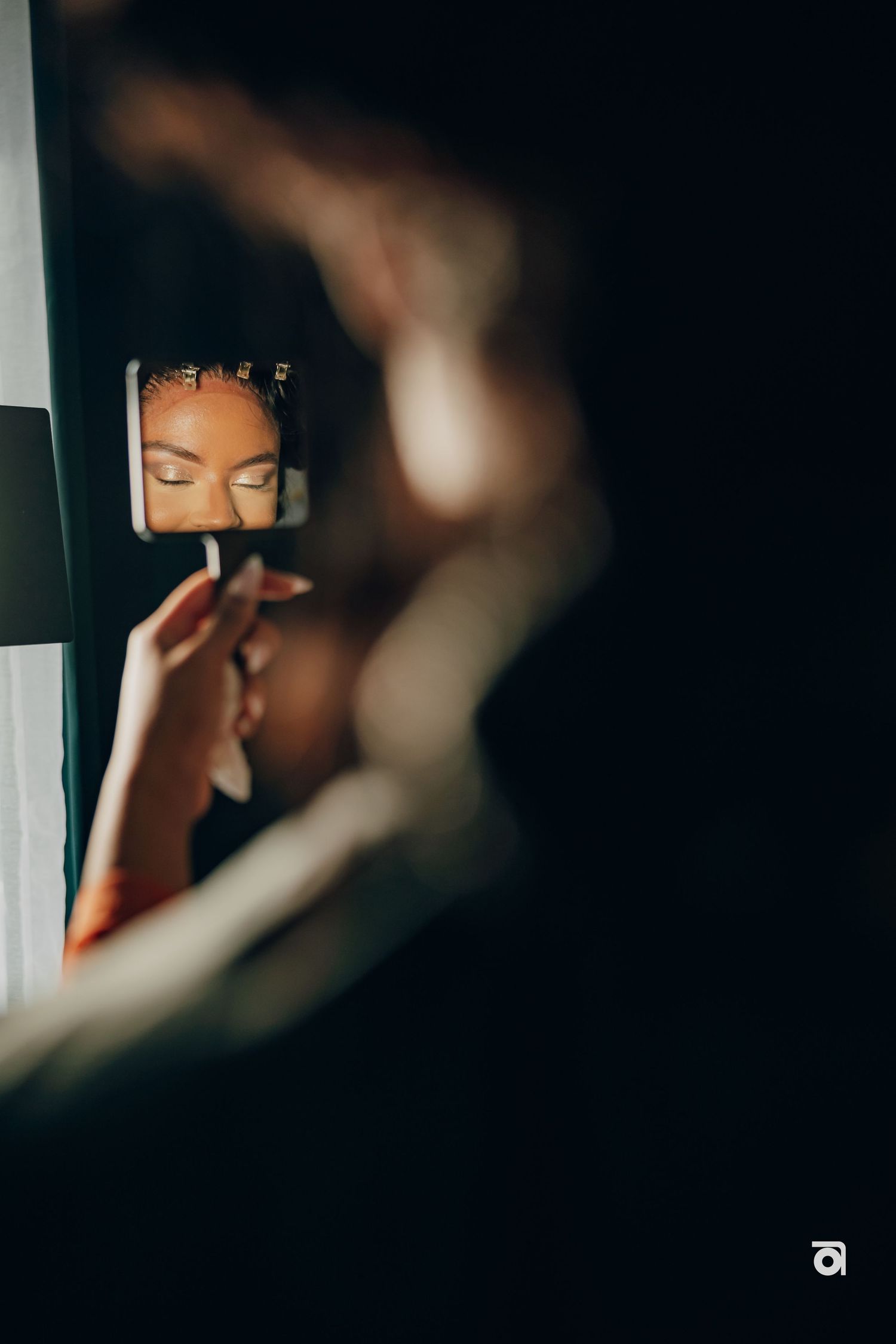 Artistic close-up reflection shot in mirror showing braided hairstyle details in moody lighting.