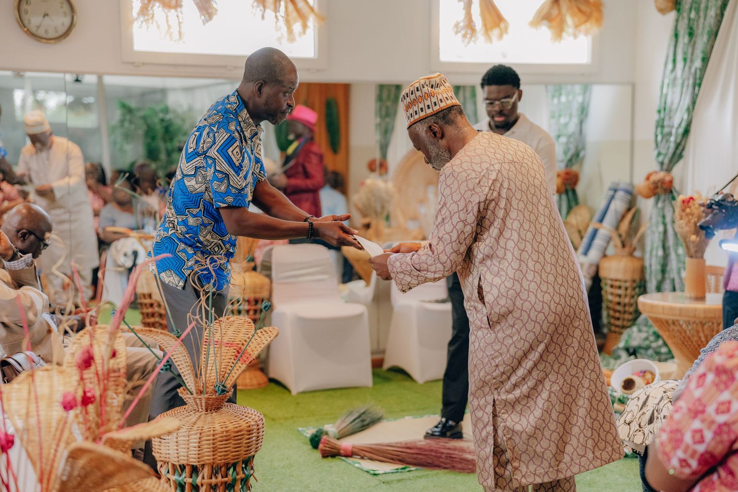 Guests celebrate at a traditional Nigerian wedding ceremony with colorful attire and dancing in an indoor venue.