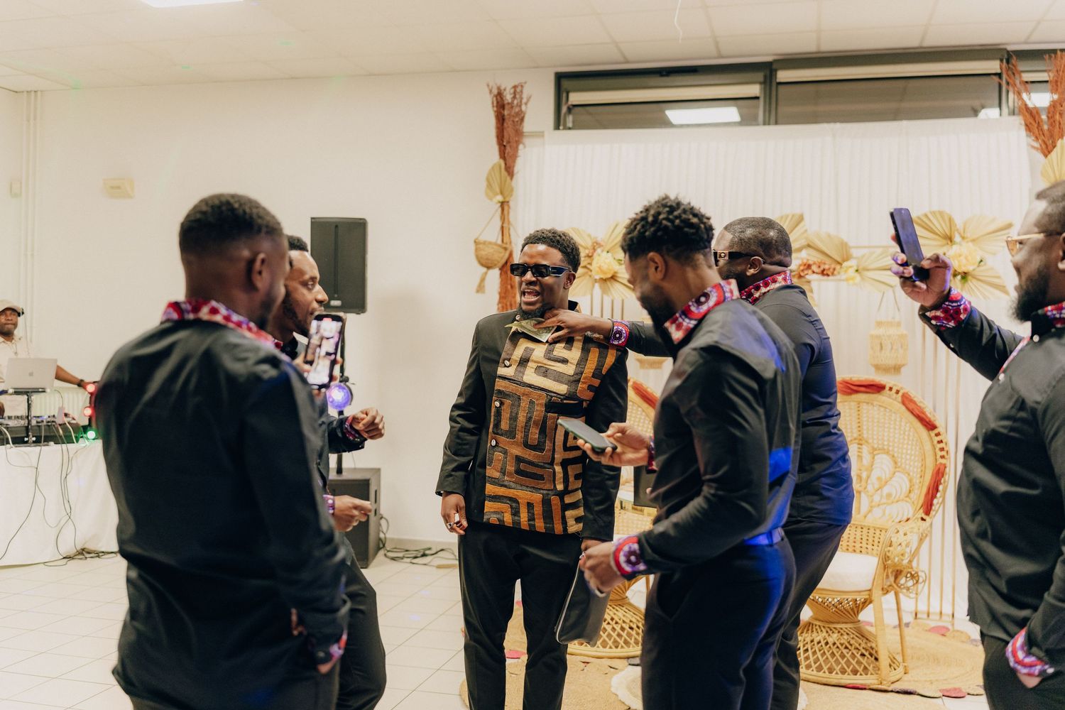 A group of people are gathered in a room together looking down at something and engaged in conversation.