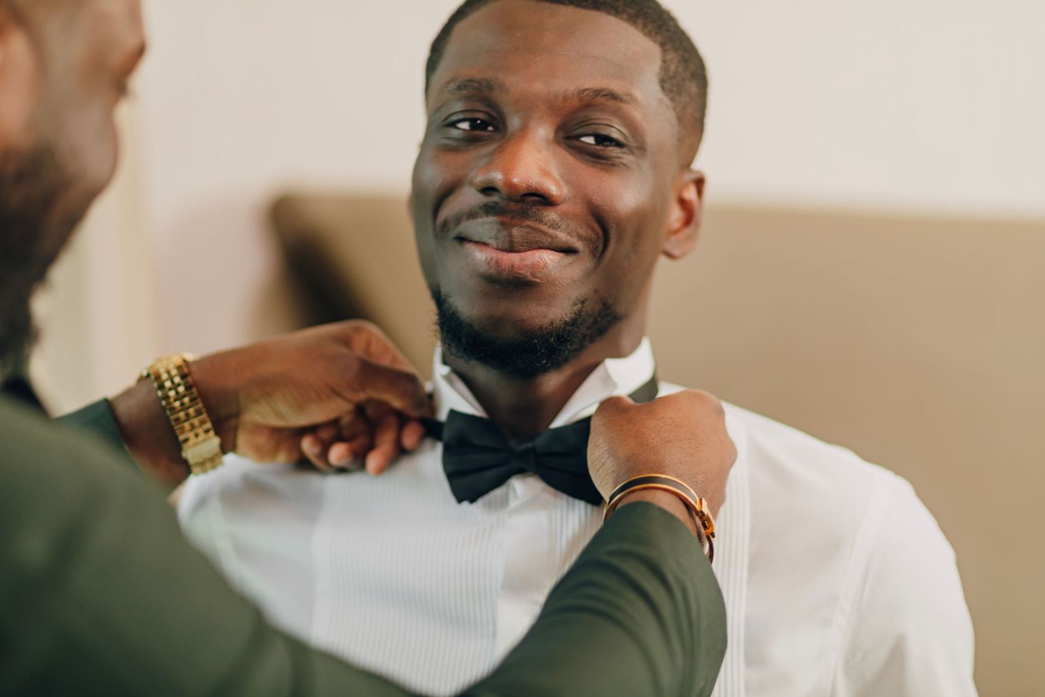 Close-up of hands adjusting a black bowtie on white formal shirt.