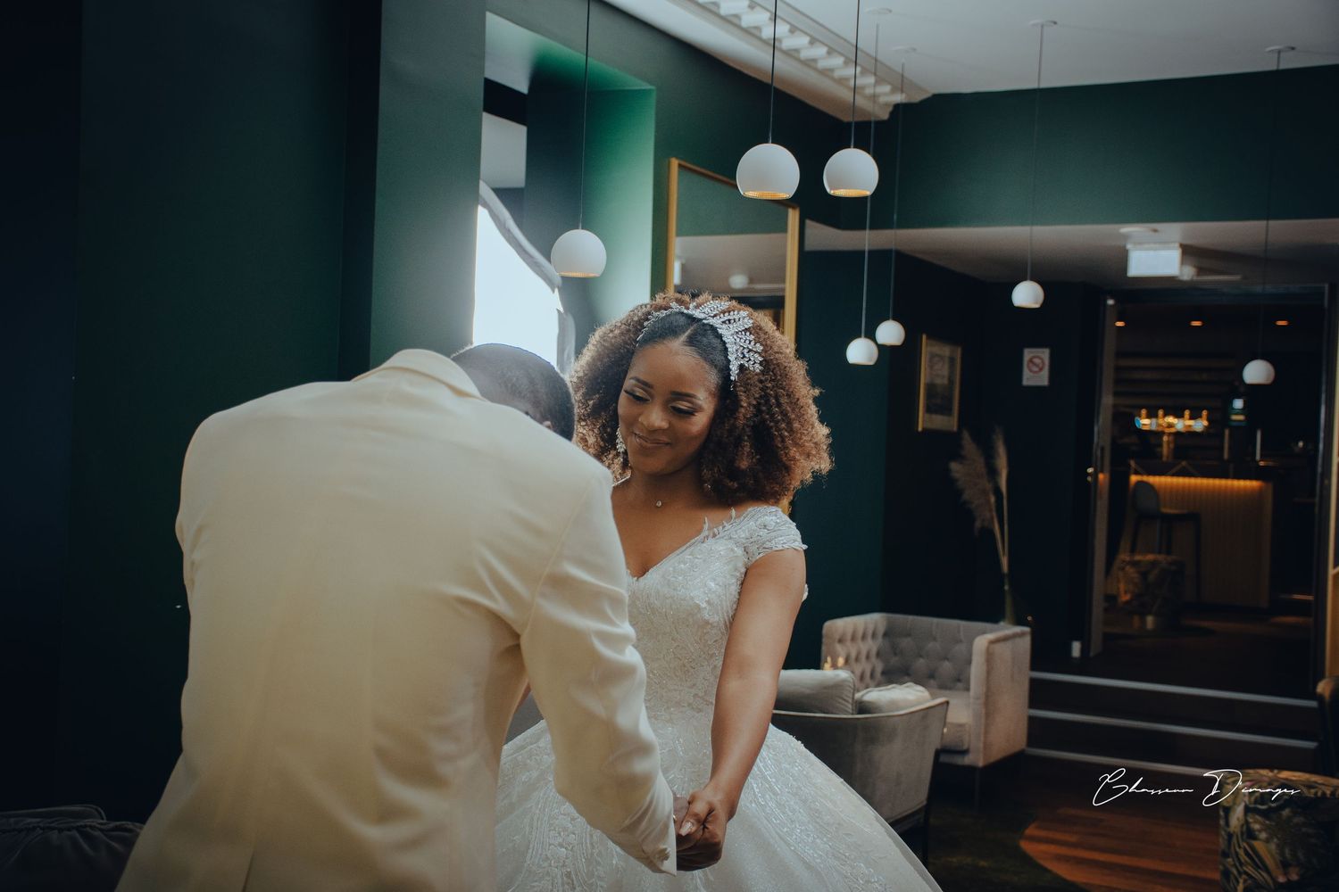 A wedding couple interacting in an elegantly decorated venue with green walls.