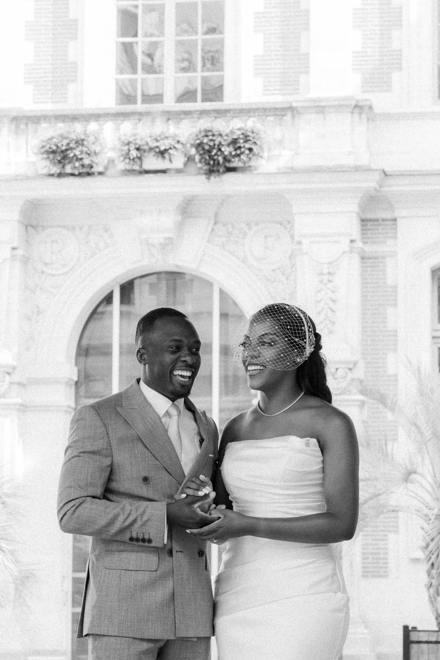 A happy couple shares joyful laughter during their wedding celebration in black and white photography.