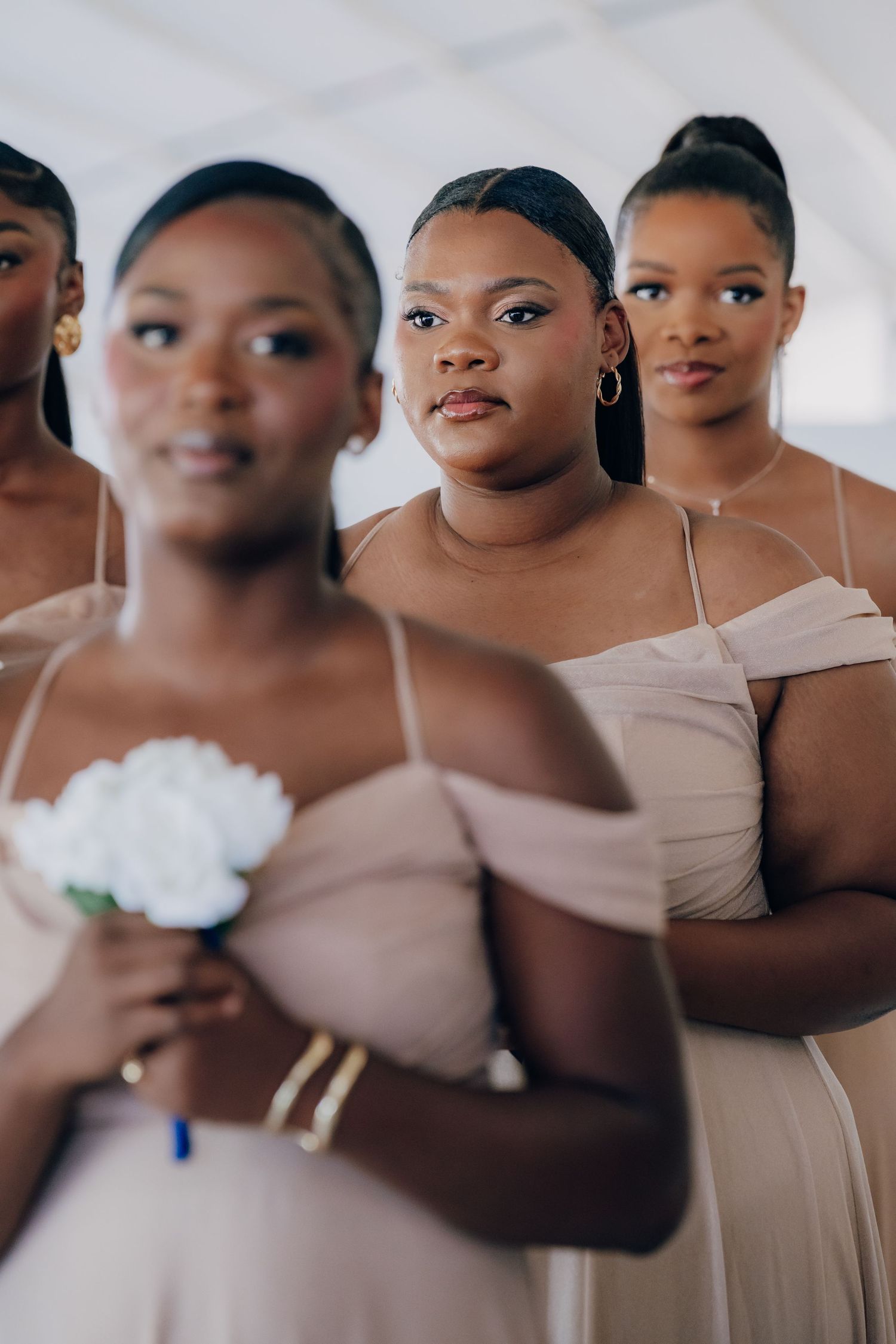 Bridesmaids in neutral beige dresses pose together during a wedding celebration.