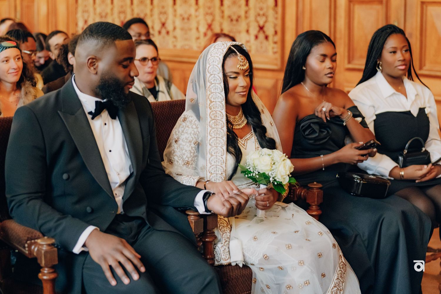 Wedding ceremony attendees seated in formal attire watching proceedings.