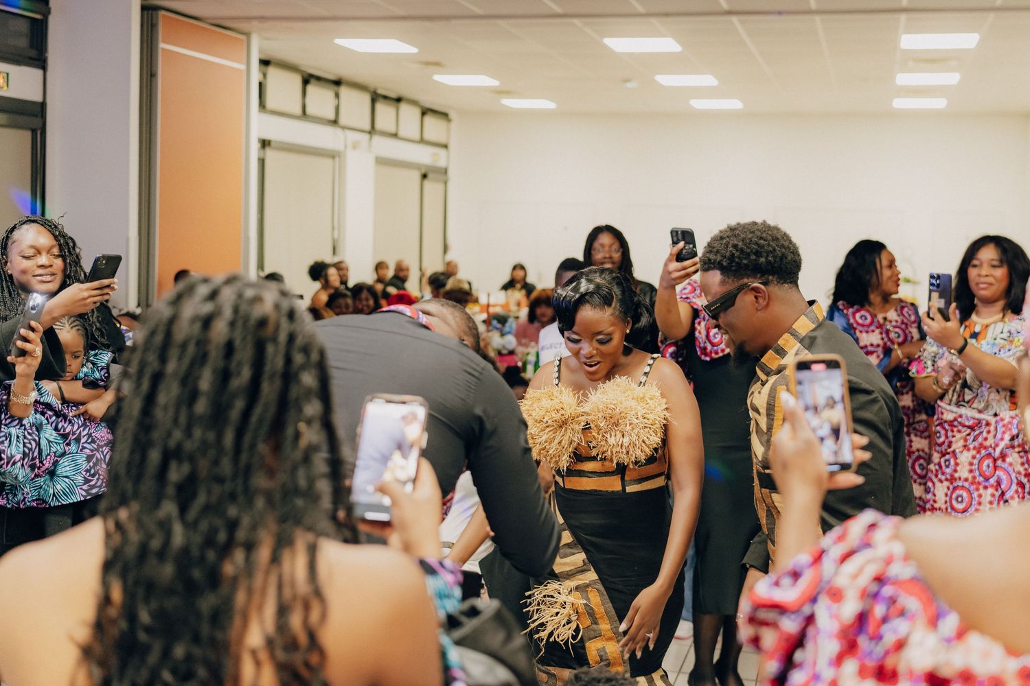 Group of attendees taking photos and mingling at an indoor social event.
