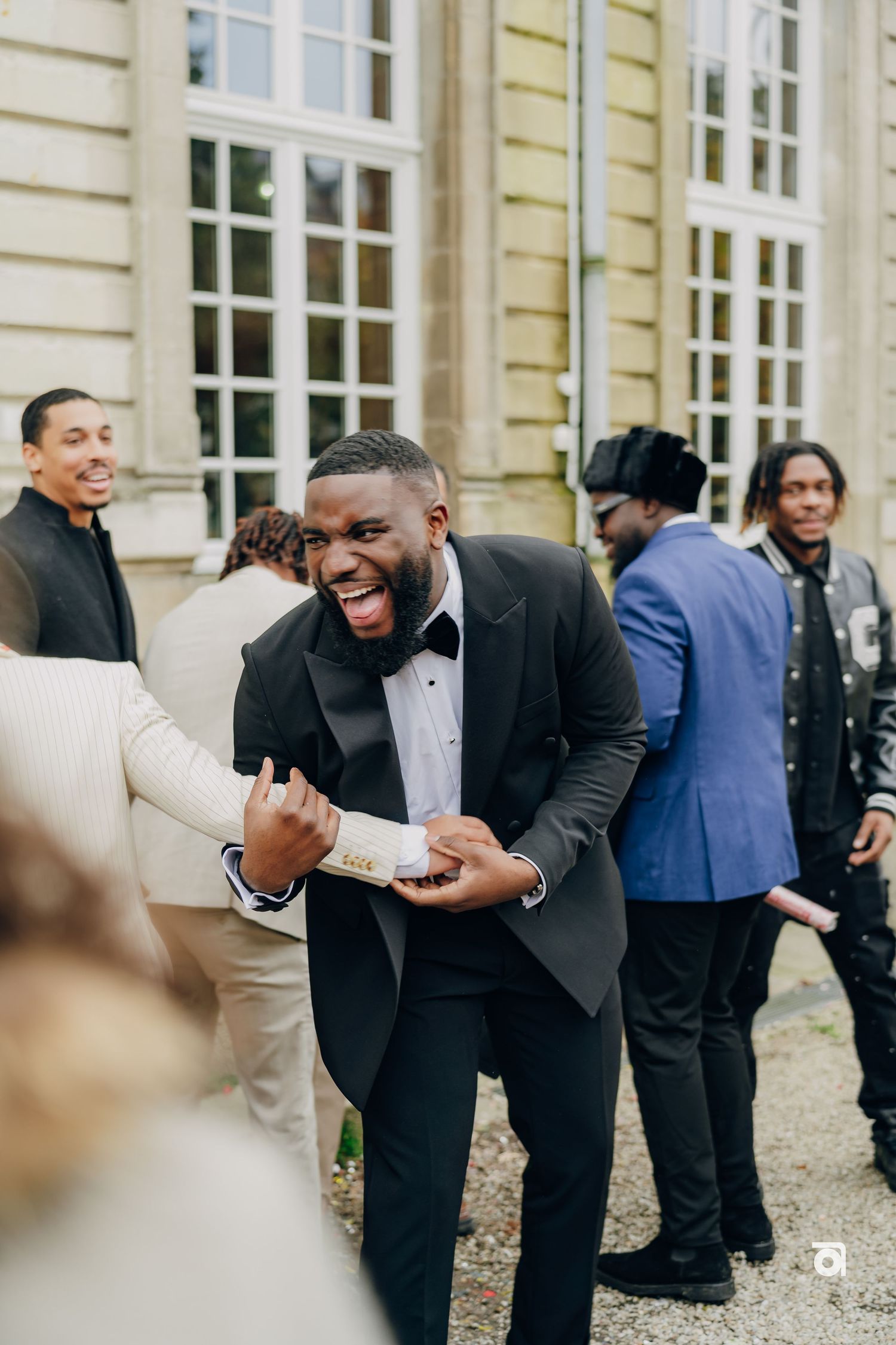 A guest in a tuxedo sharing an enthusiastic moment of joy outside an elegant venue.