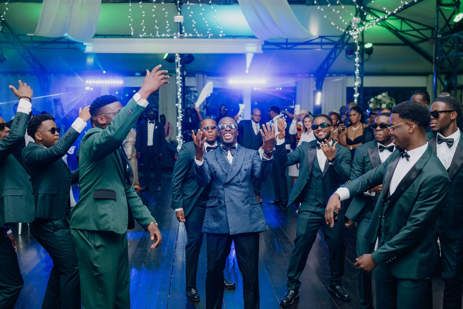 Large group of formally dressed guests dancing and celebrating at an evening event.