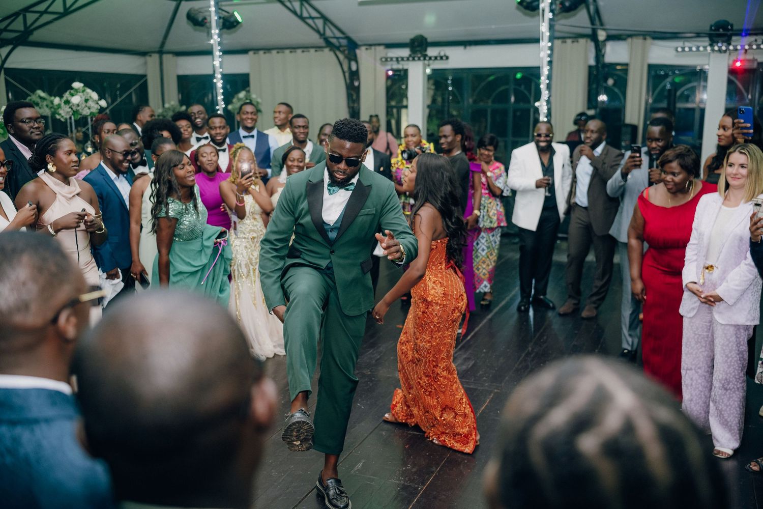 Wide shot of an indoor wedding reception with guests dancing and celebrating.