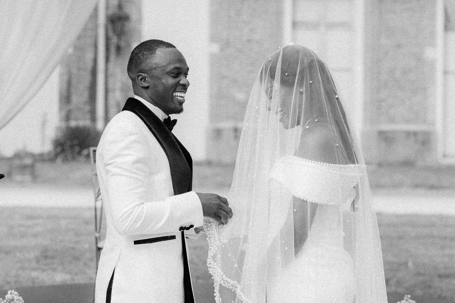 Black and white photo of a wedding ceremony under white draping outdoors.
