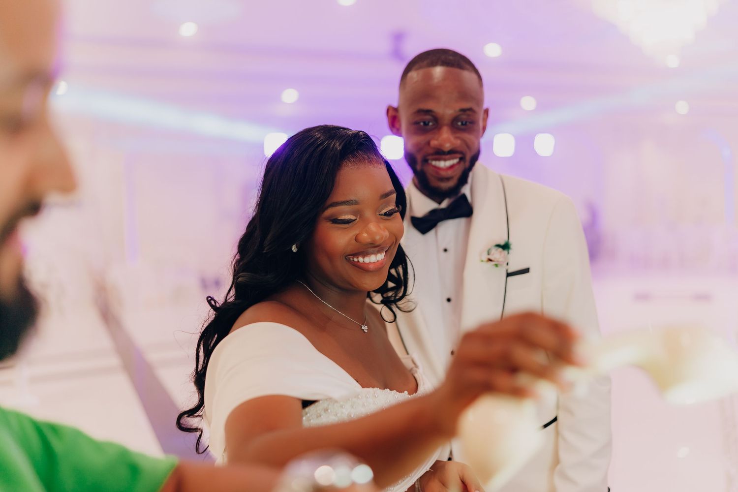 Wedding guests dancing and celebrating on a pink-lit dance floor at a reception party.