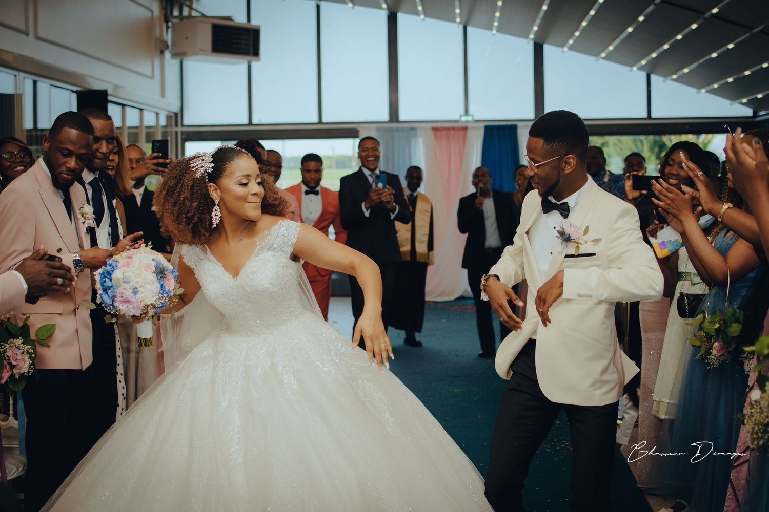 Joyful dancing and celebration during wedding reception under decorative lighting.
