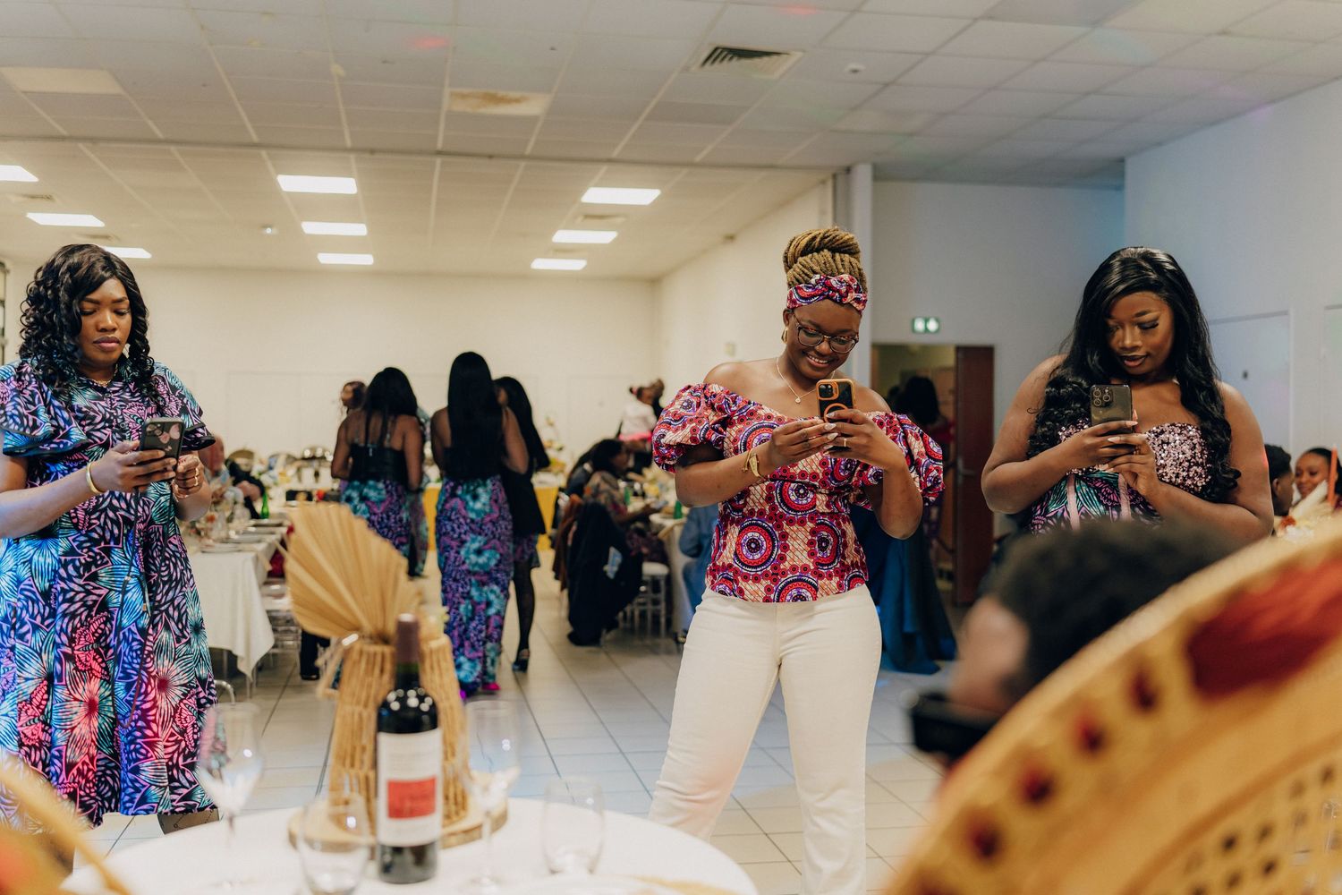Party guests dance and celebrate in a room decorated with colorful attire and festive decorations.