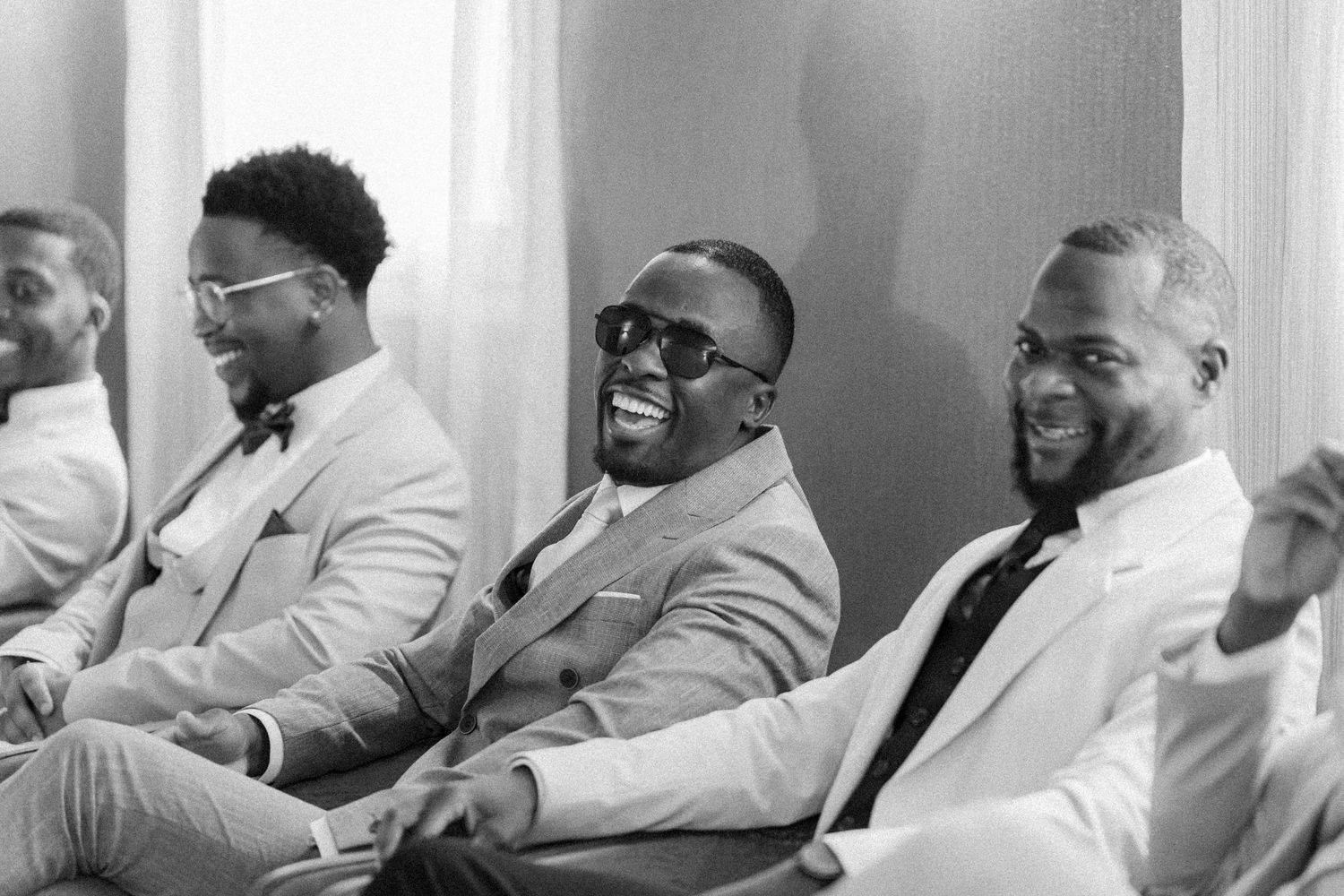 A group of people dressed in light colored suits sit together in a row.
