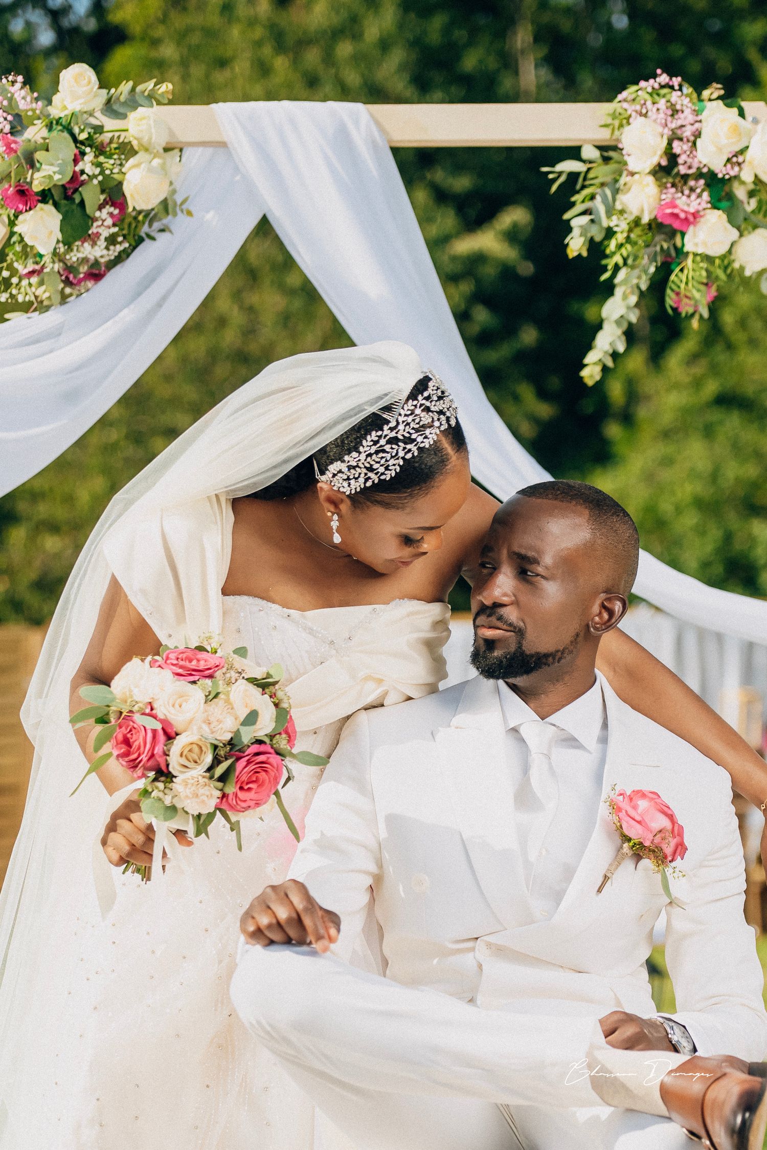 Romantic wedding portrait under white draped arch decorated with pink and white flowers.