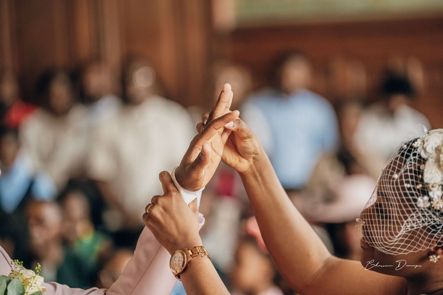 Close-up of hands clasped together during wedding celebration with jewelry details.