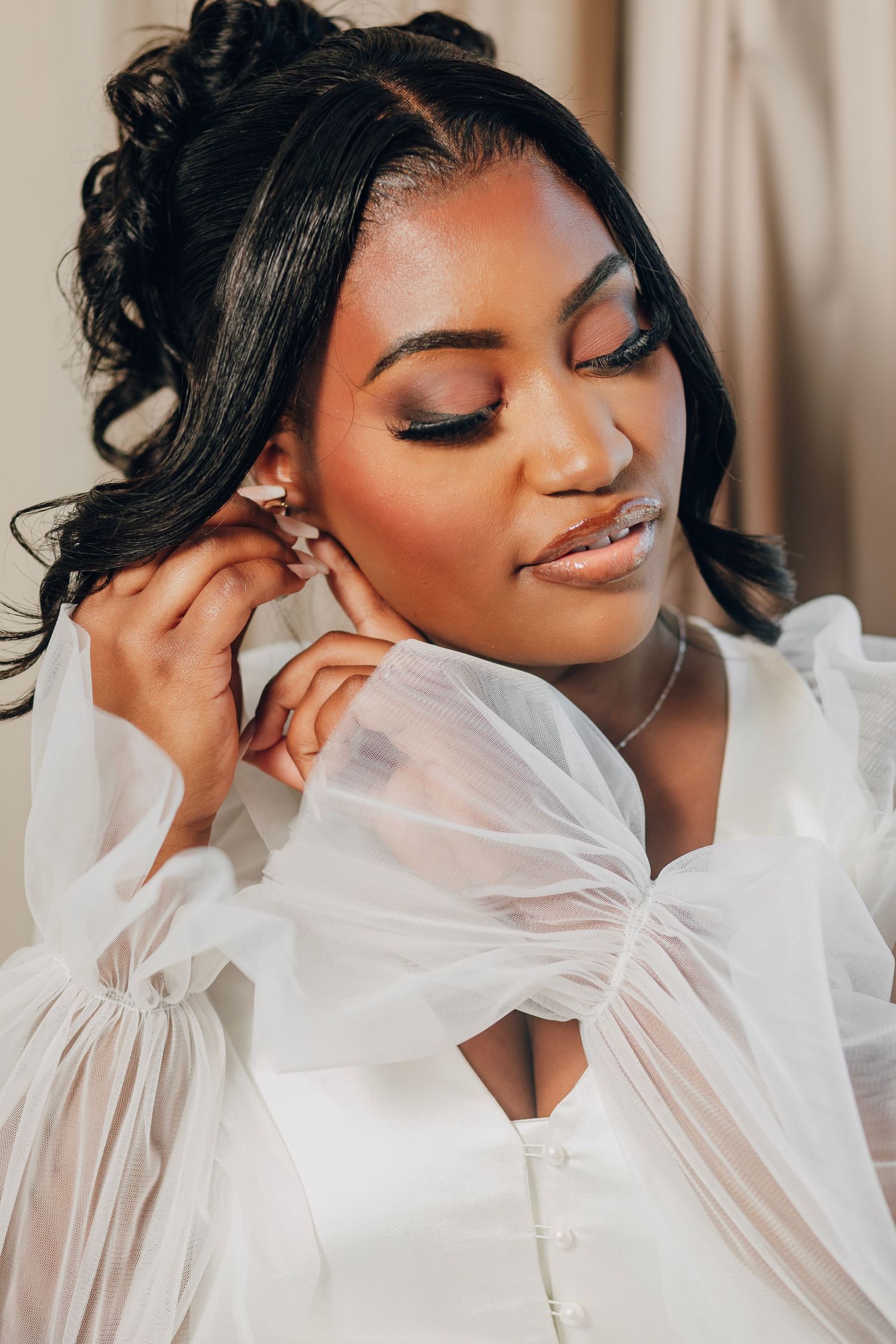 Soft bridal portrait featuring delicate sheer sleeves and glamorous eye makeup.