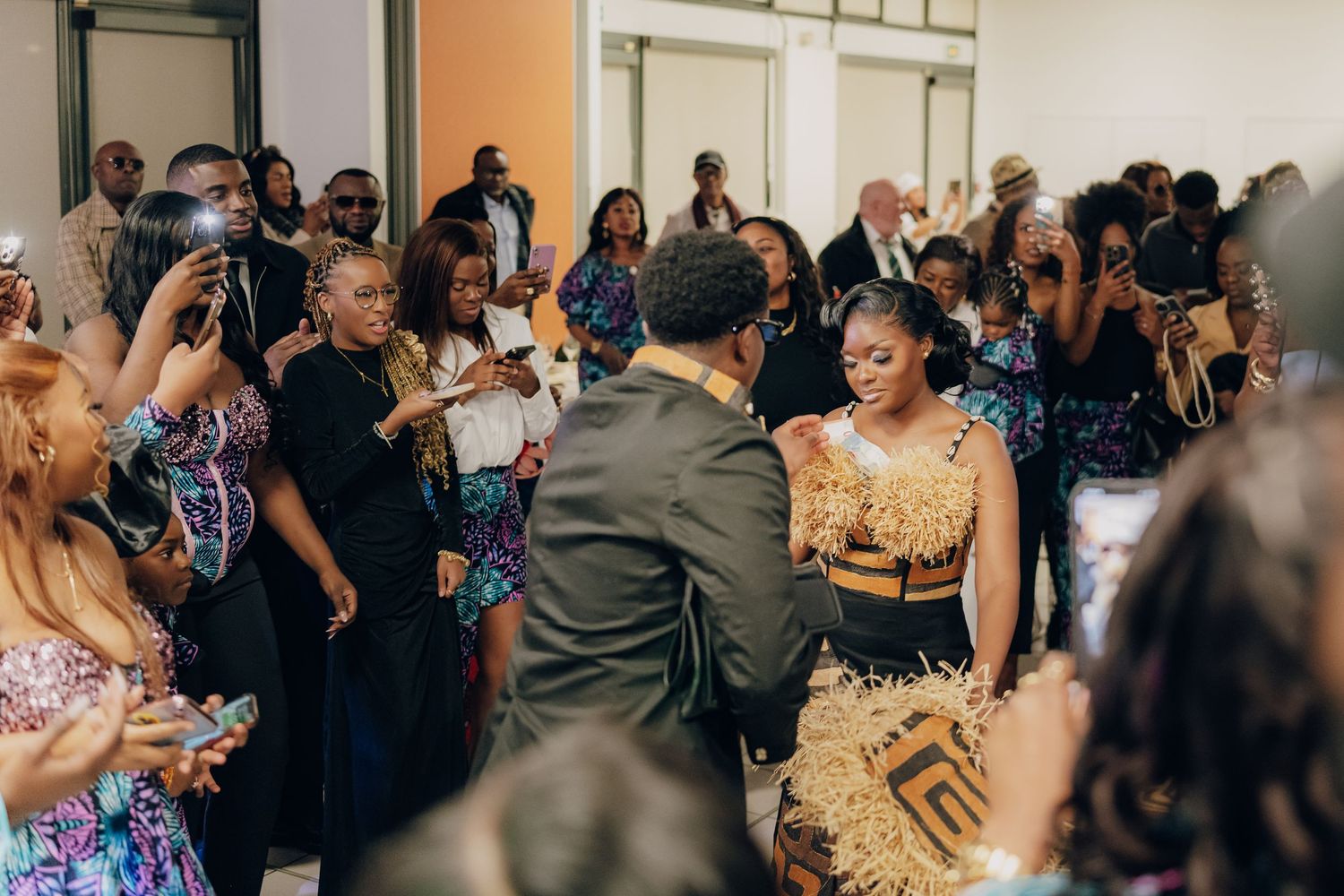 A lively crowd of wedding guests dancing and celebrating together at an indoor reception venue.