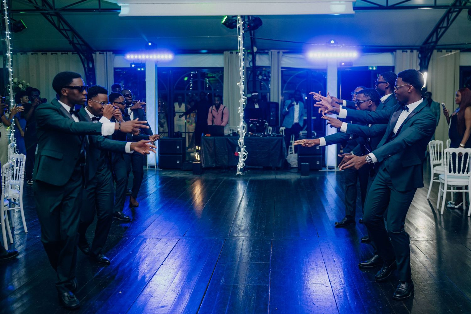Large wedding reception venue with blue lighting and guests dancing on spacious dance floor.
