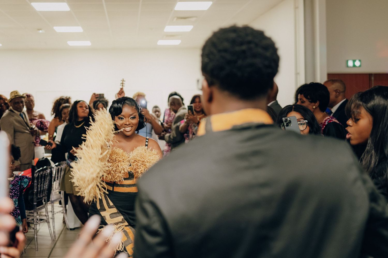 A celebration in a bright indoor venue with attendees in formal attire dancing and smiling.