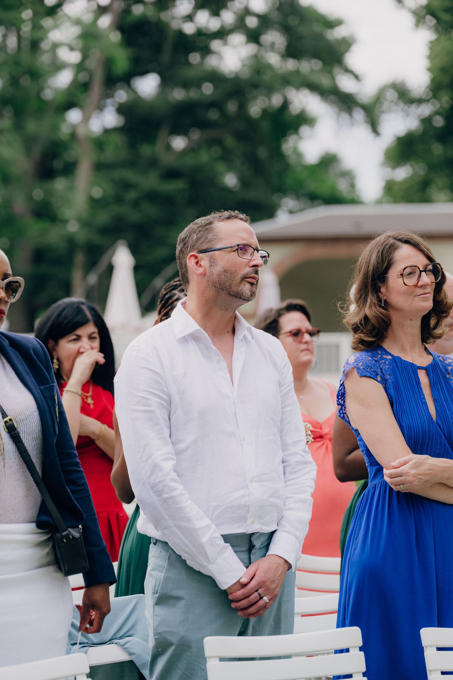 Wedding guests watching ceremony outdoors wearing casual summer attire.