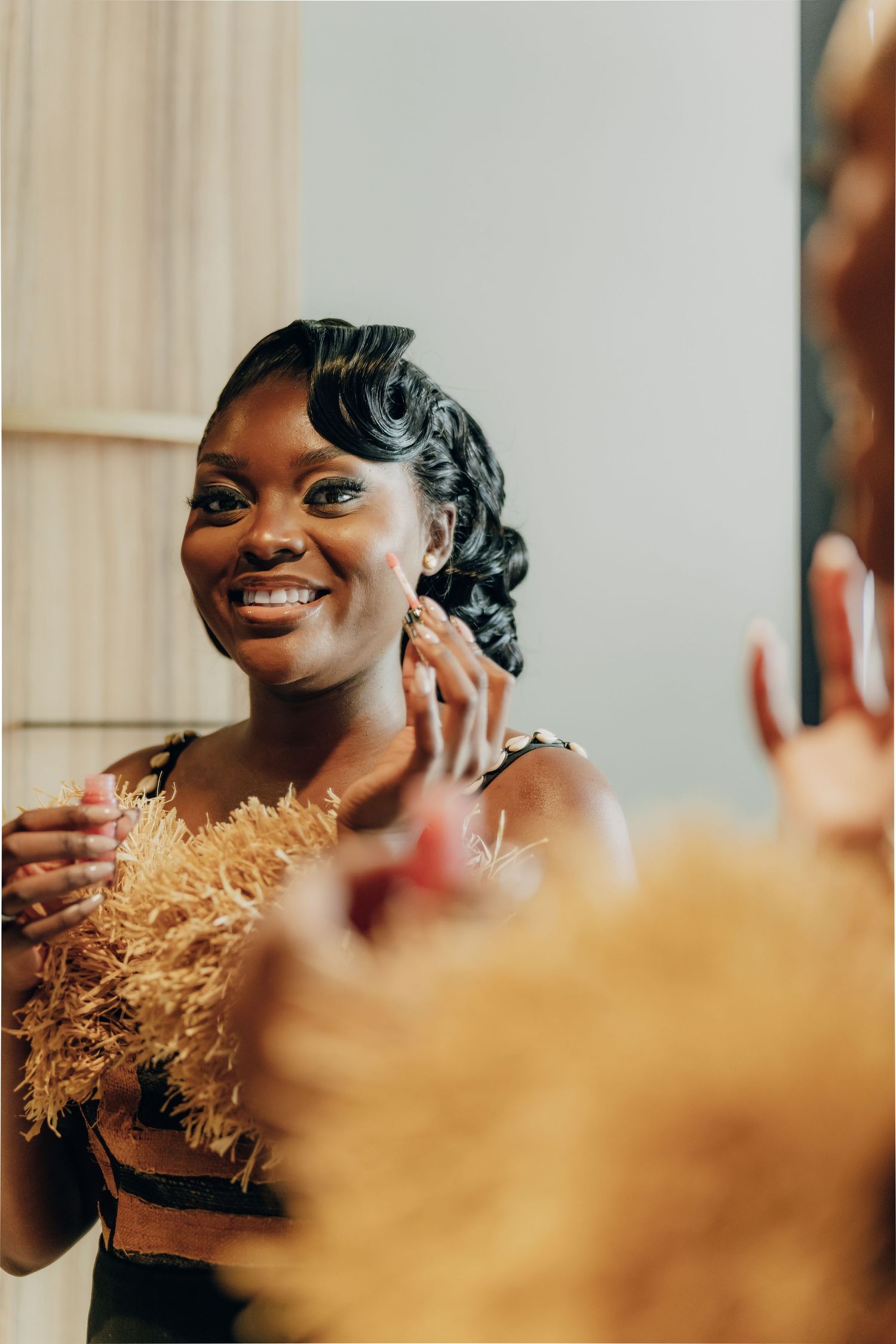 A radiant bride with elegant curled hairstyle smiles warmly while wearing a black dress with delicate floral accents.
