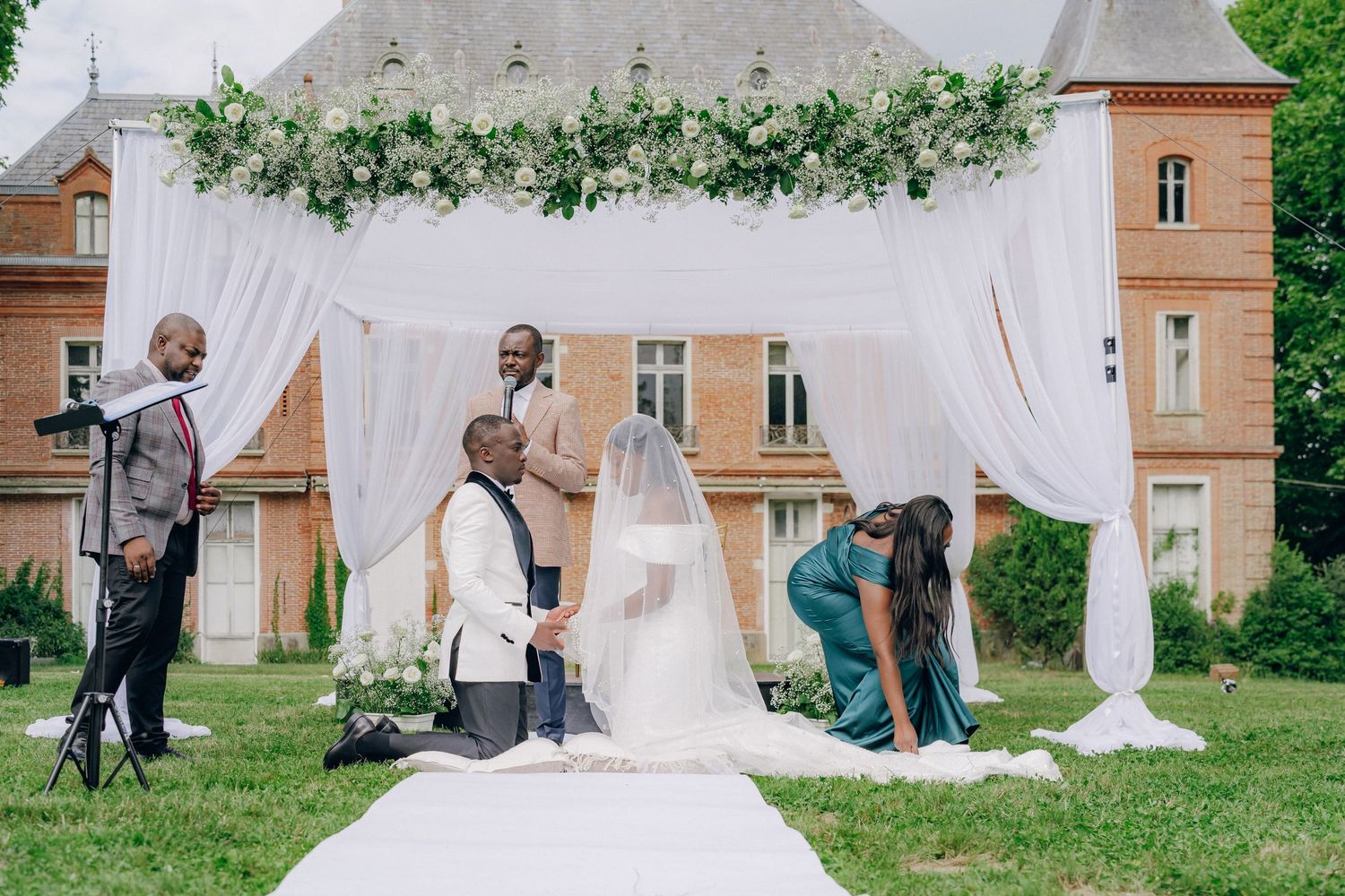 Wedding ceremony moments captured under a white draped canopy with greenery decorations.