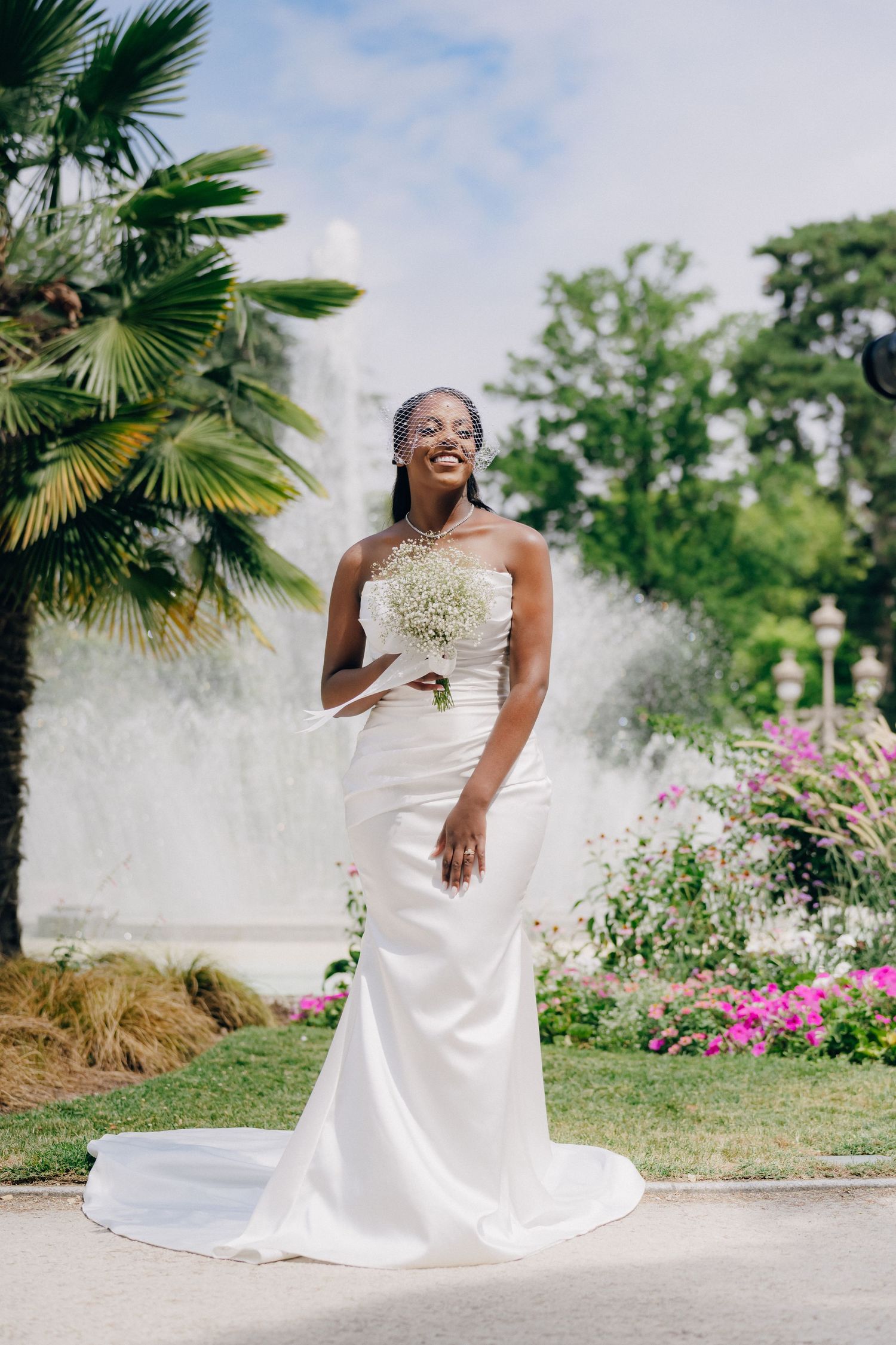Joyful bridal portrait sequence in a tropical garden with palm trees and pink flowers.