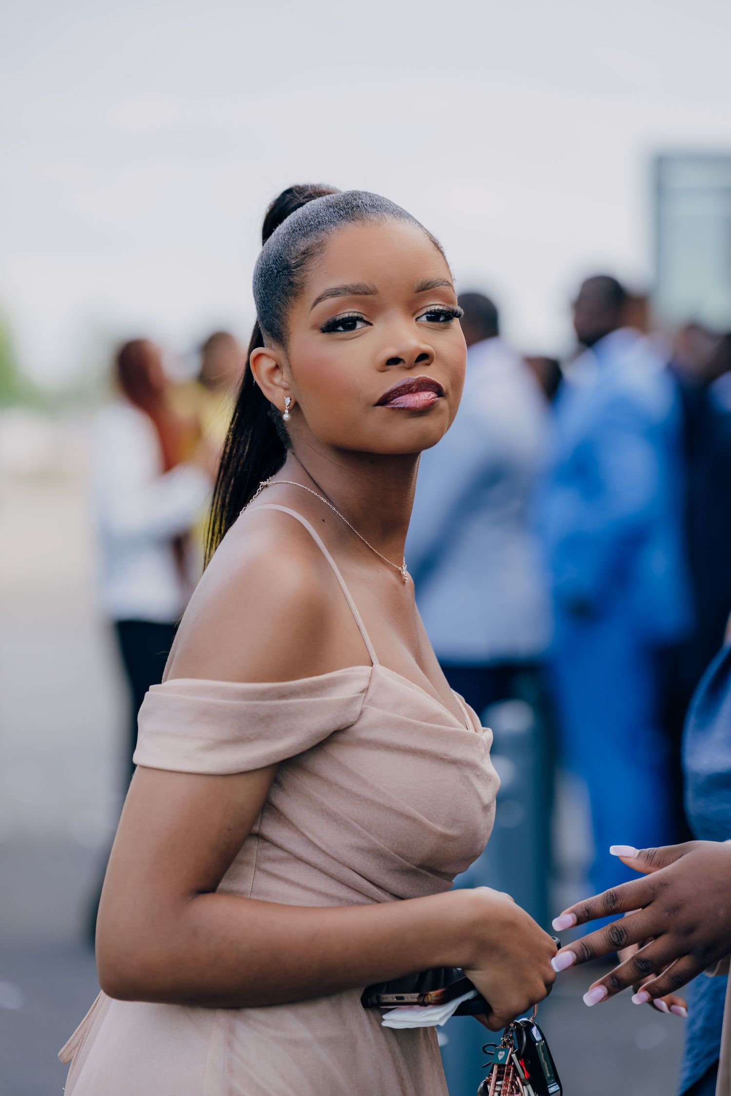 Wedding guest in blush off-shoulder dress dancing at reception venue.