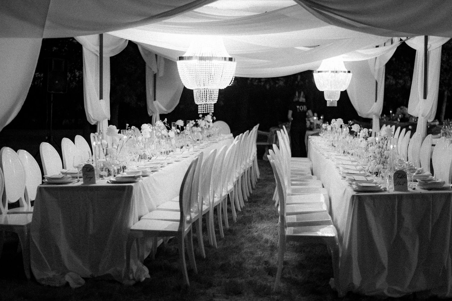 Black and white wedding reception setup with elegant table settings and draped fabric decor throughout the venue.