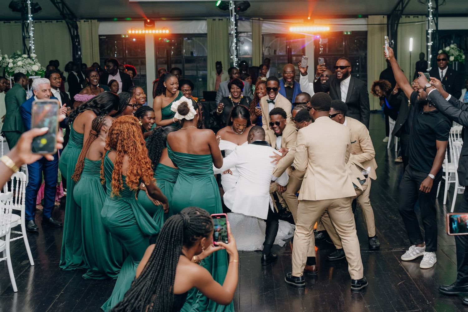 Wedding reception dance floor filled with guests celebrating under warm lighting.