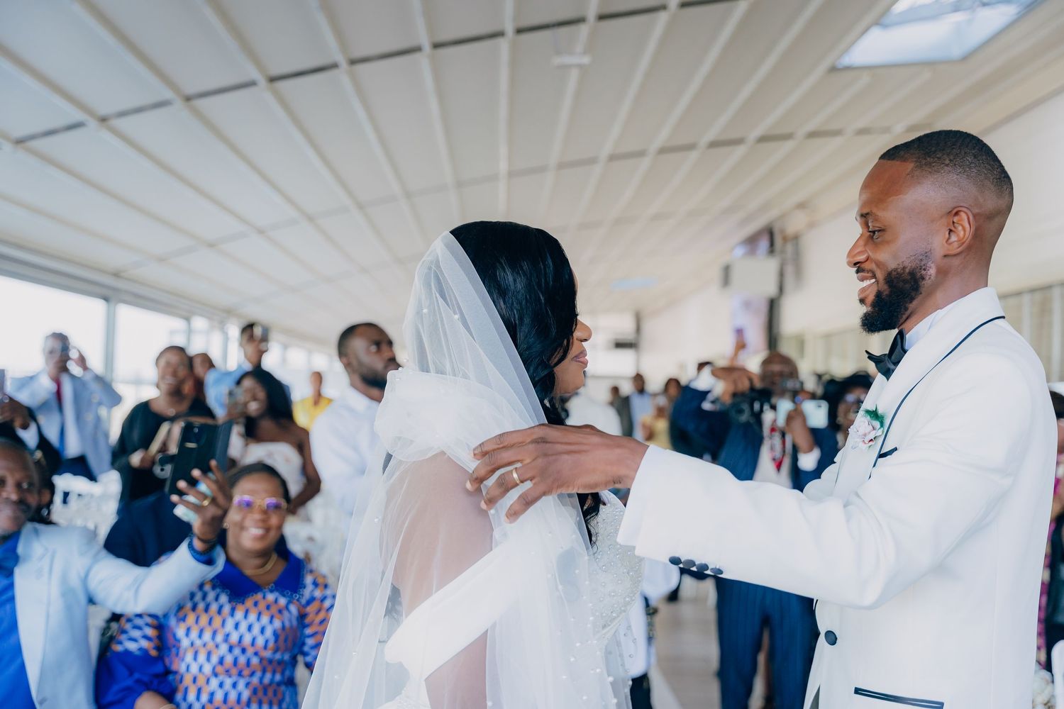 Wedding reception venue with white decor and guests mingling in formal attire.