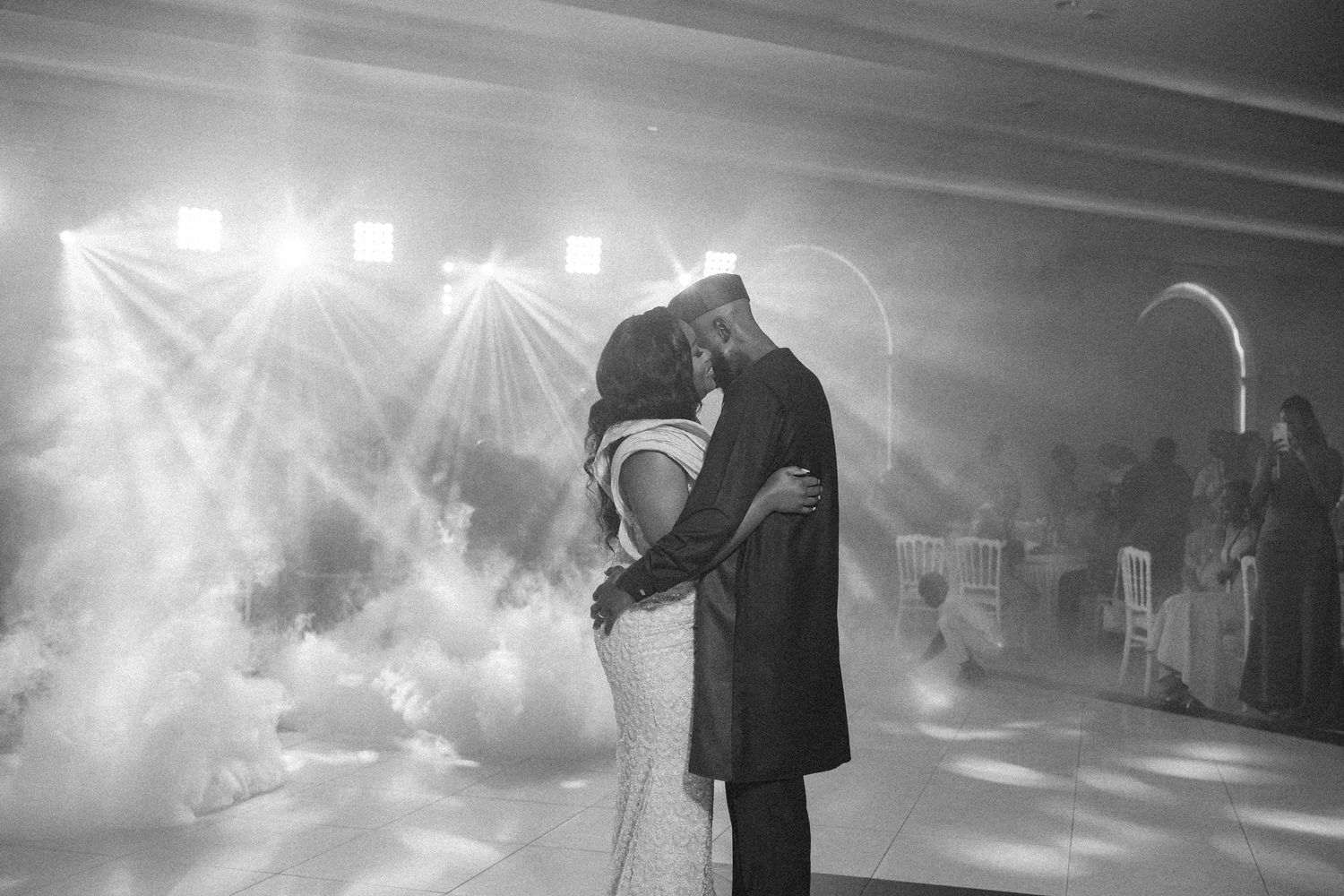 A couple shares their first dance amid dramatic fog and lighting effects at their reception.