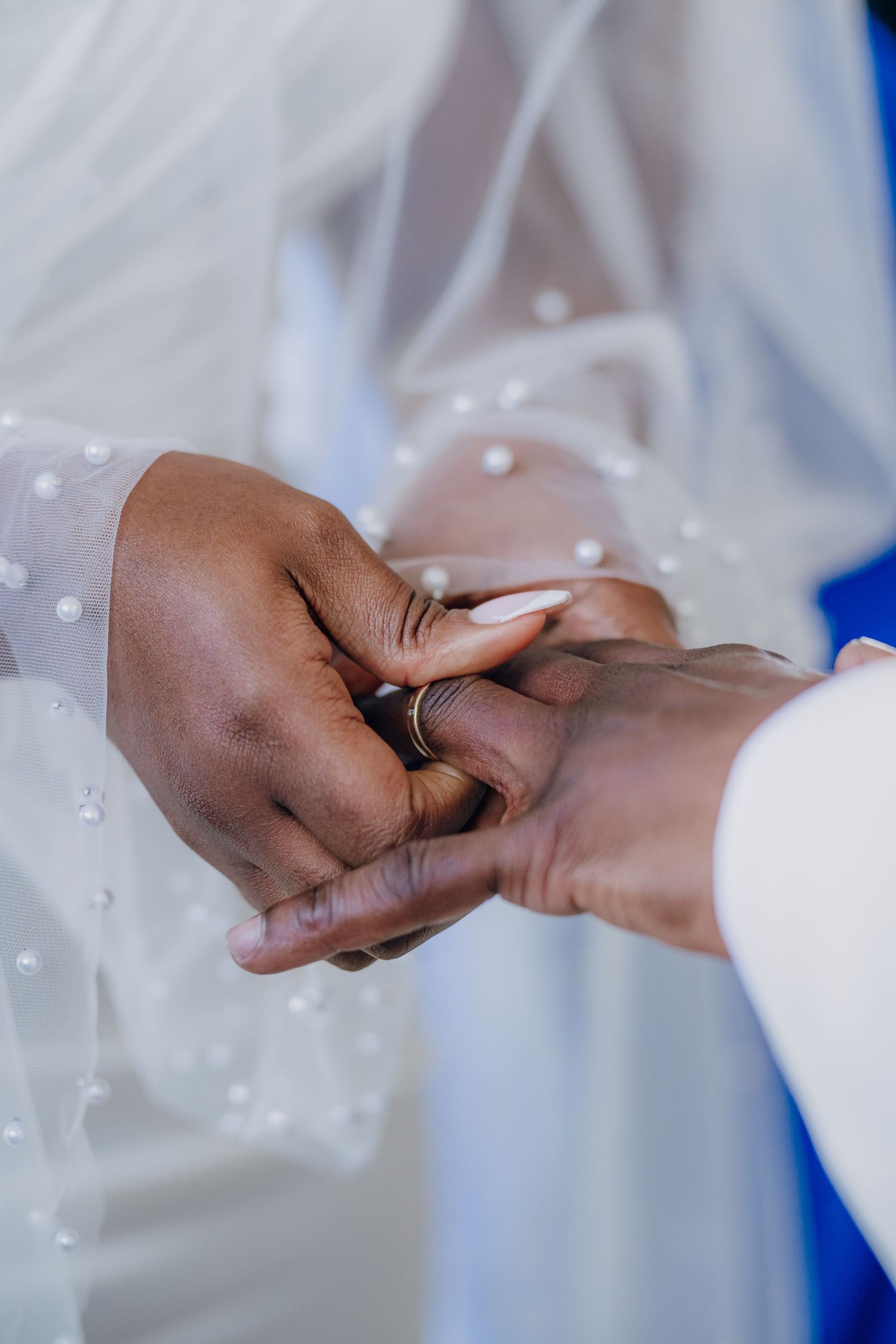 Close-up of hands exchanging wedding rings during a ceremony.