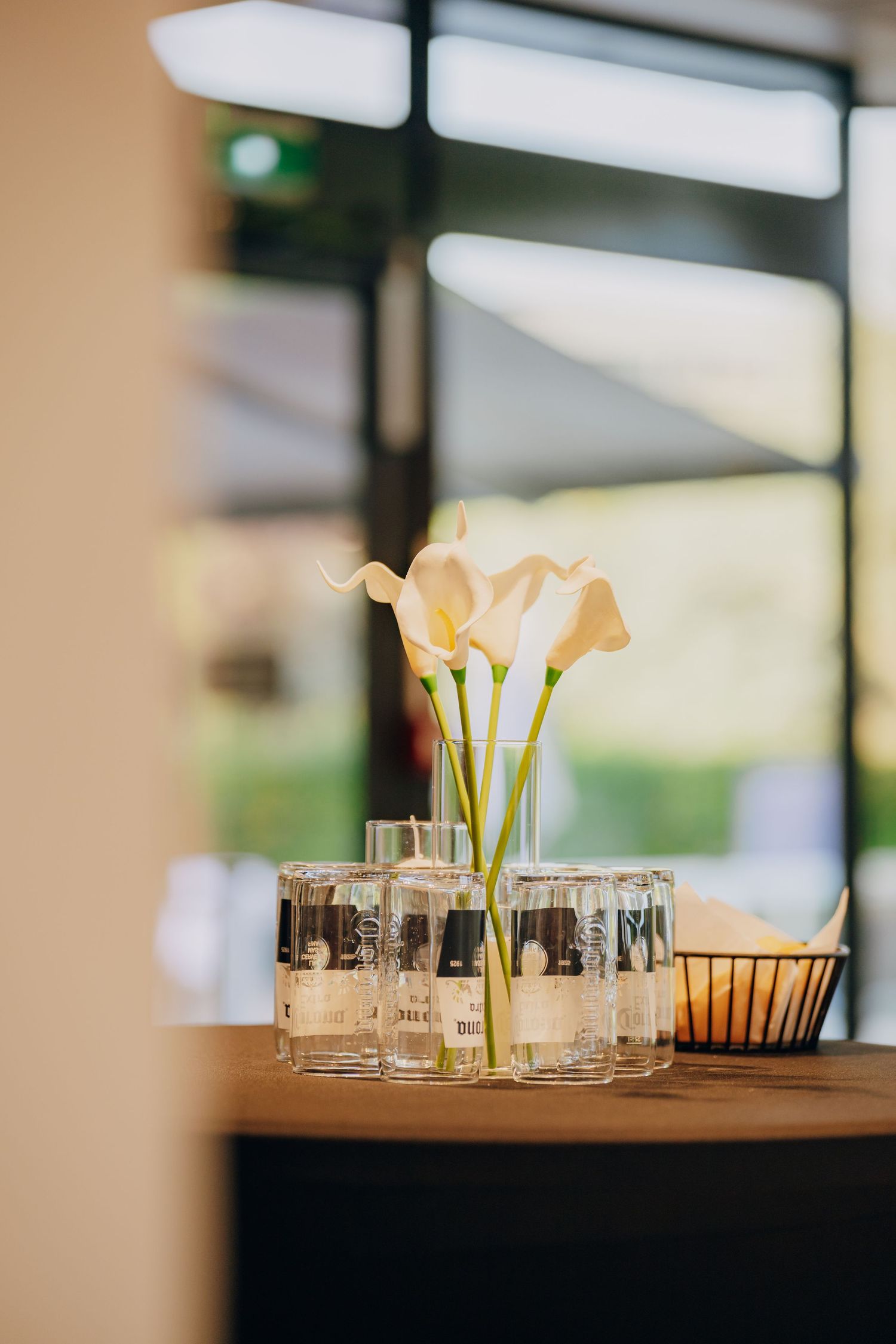 White calla lilies in glass vases create an elegant table centerpiece display with soft window lighting in the background.