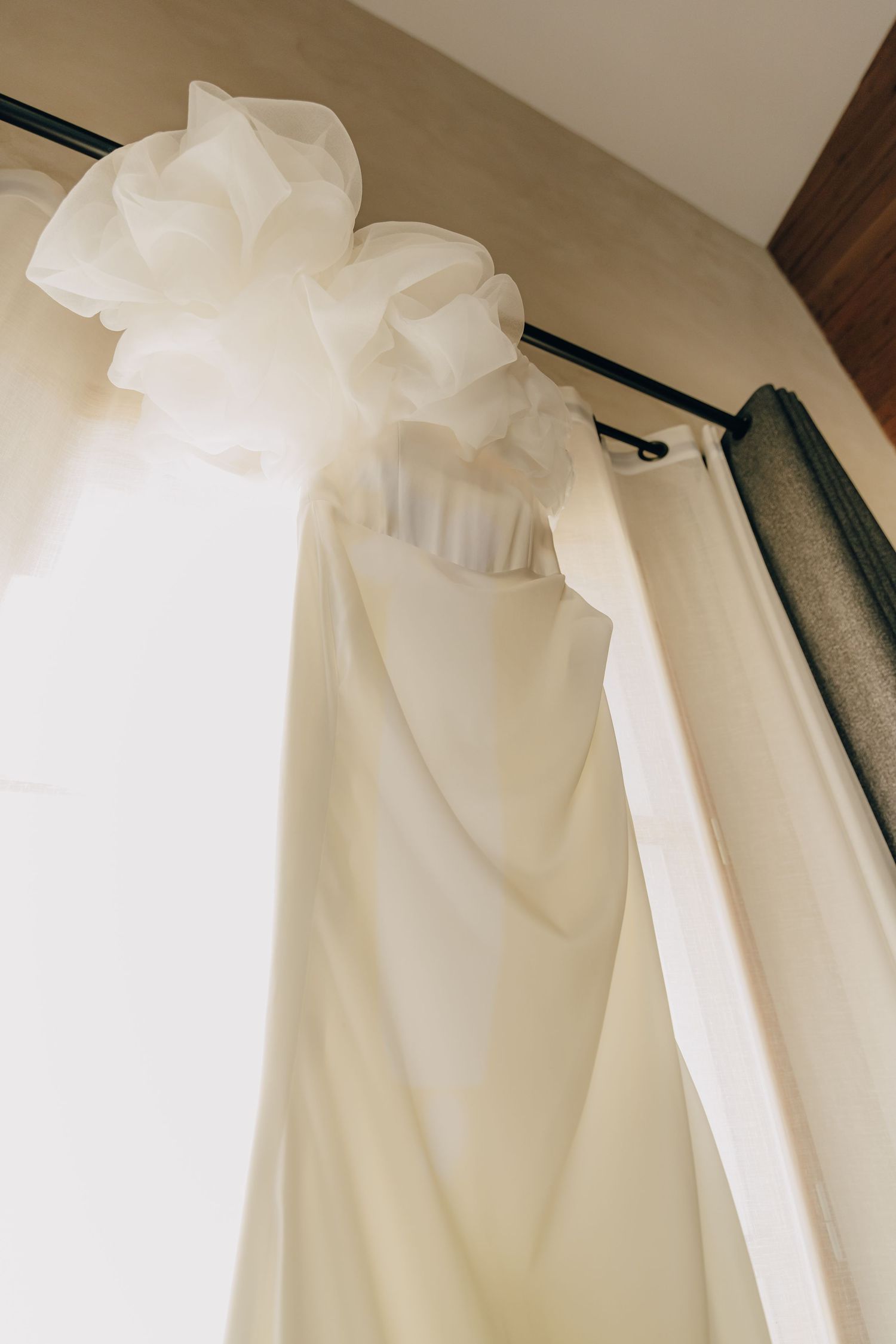 Close-up of white wedding dress details hanging on display.