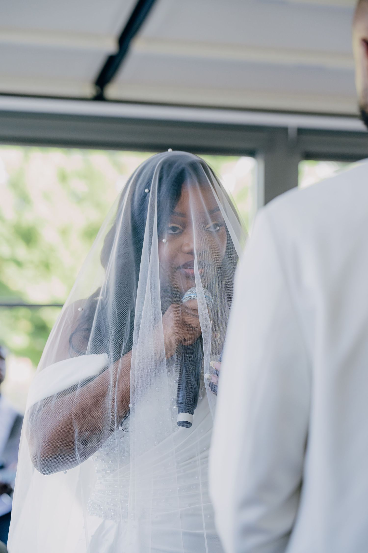 A singer wearing a wedding veil performs with a microphone during a ceremony.
