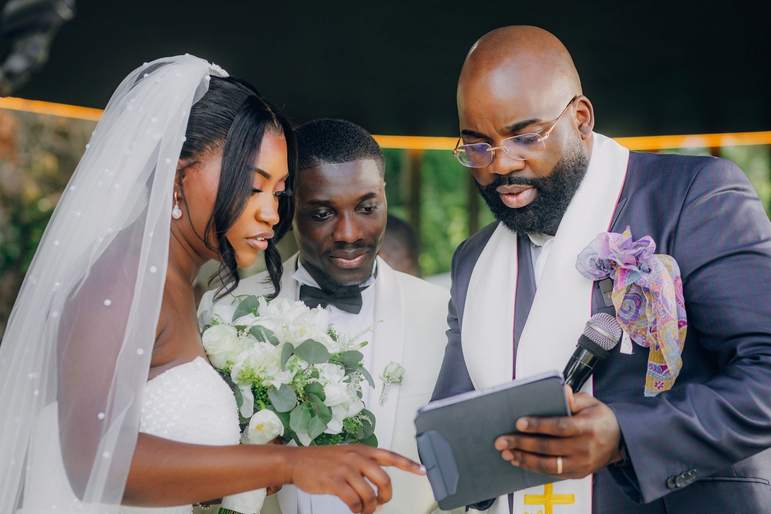 Wedding party members gather around to look at a tablet during the ceremony.