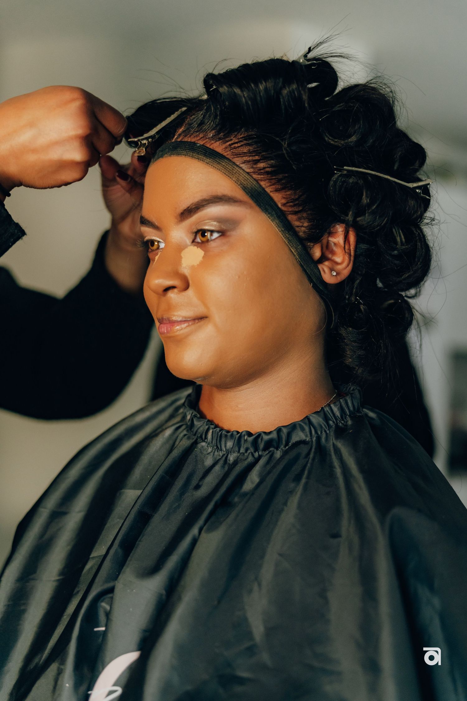 A styling session shows someone having their hair arranged while wearing a dark protective cape.