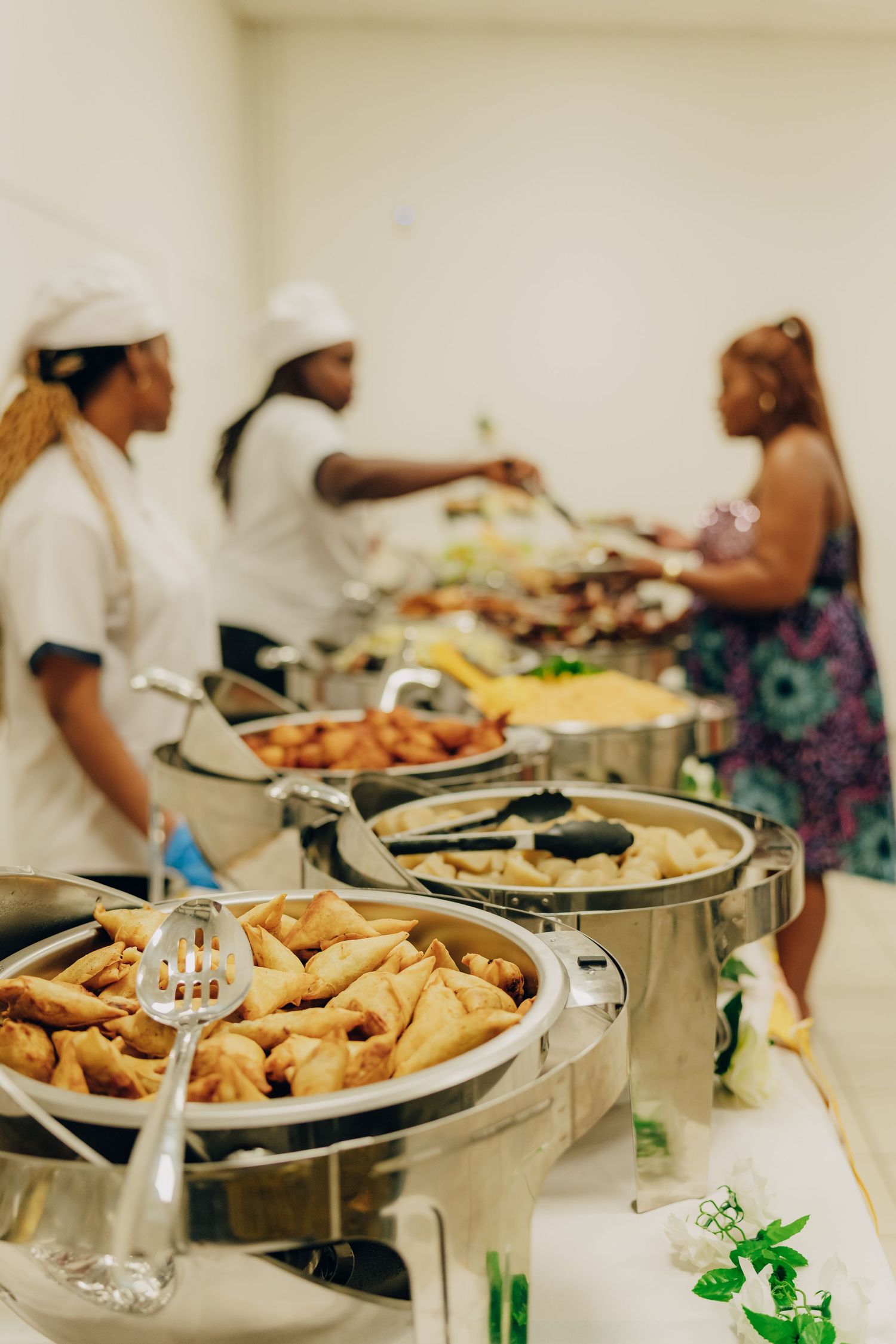 Buffet line with chafing dishes of food and people serving themselves.