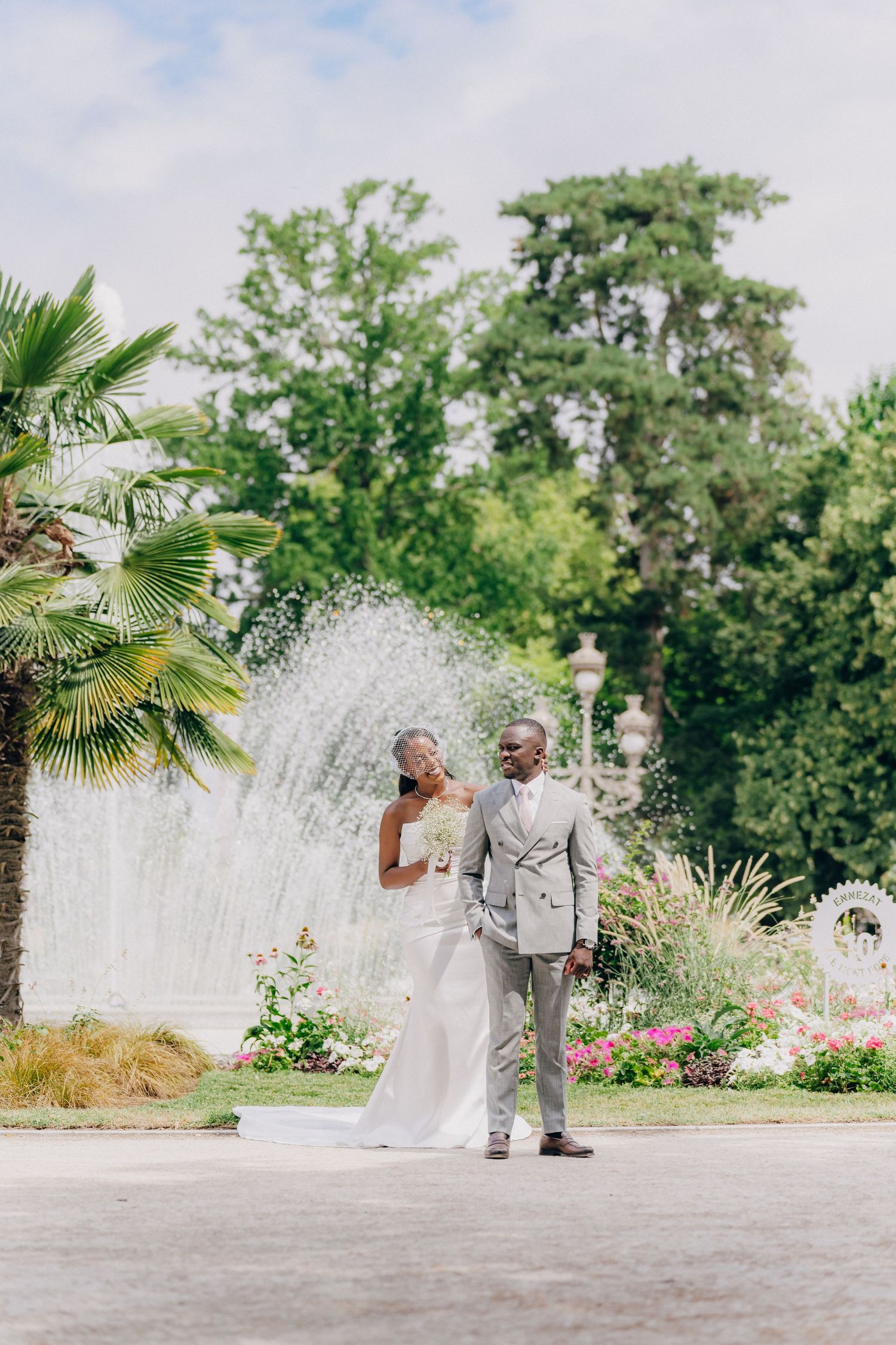Elegant outdoor wedding scene in a garden with fountains and palm trees creating a romantic tropical atmosphere.