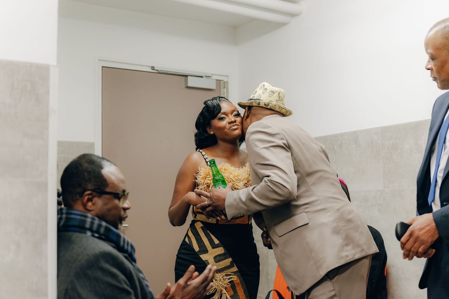 A group of people share a joyful moment together in a bright indoor hallway.