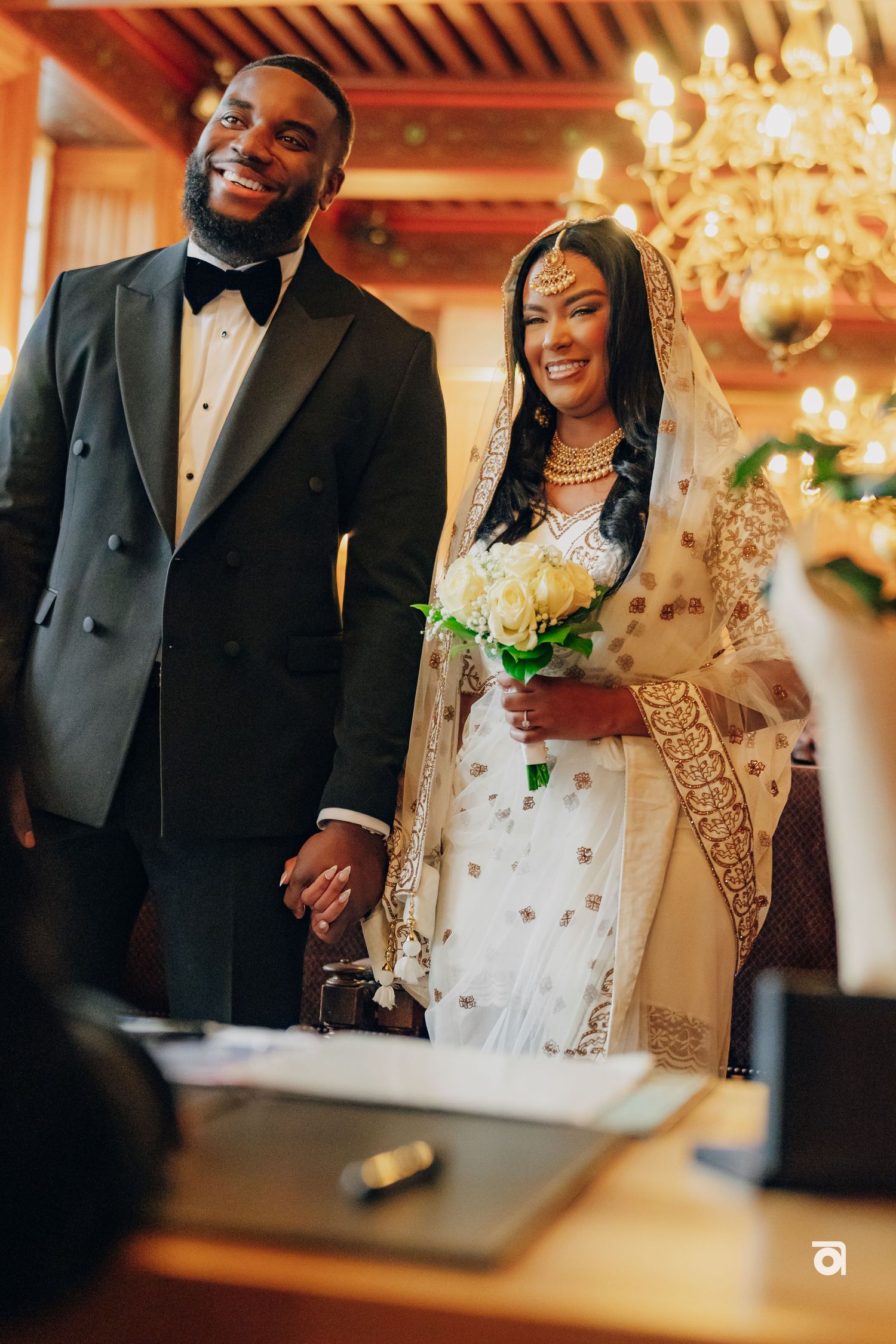 A joyful couple shares a moment during their wedding celebration in an elegantly lit room.