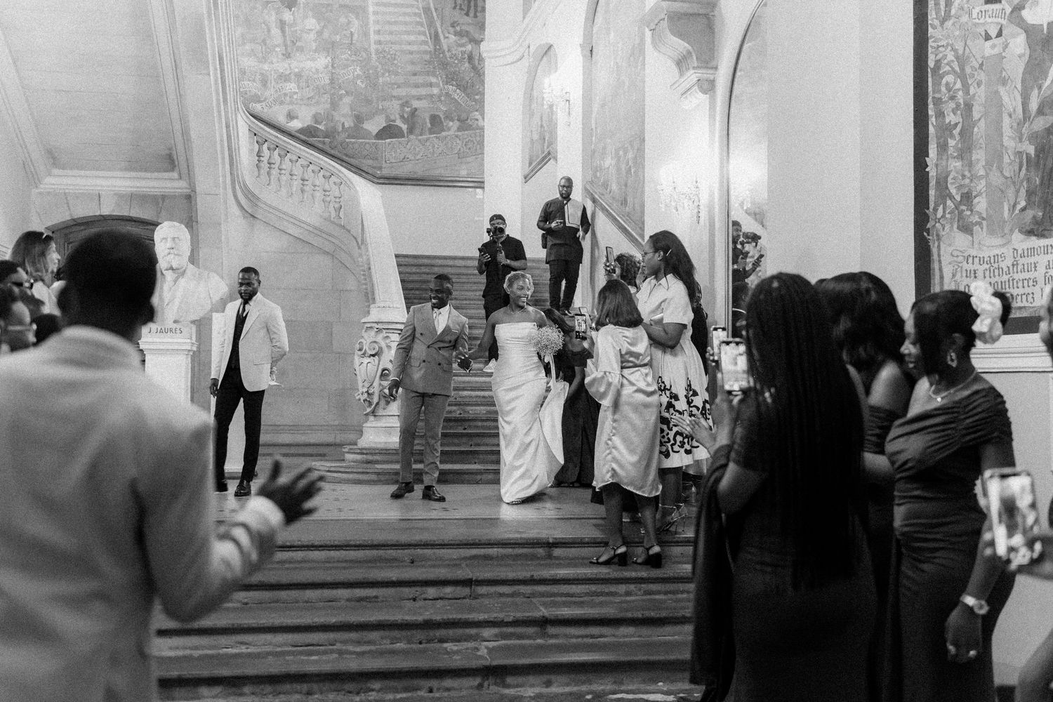 Black and white photo of wedding celebration in historic palace interior with decorative walls.
